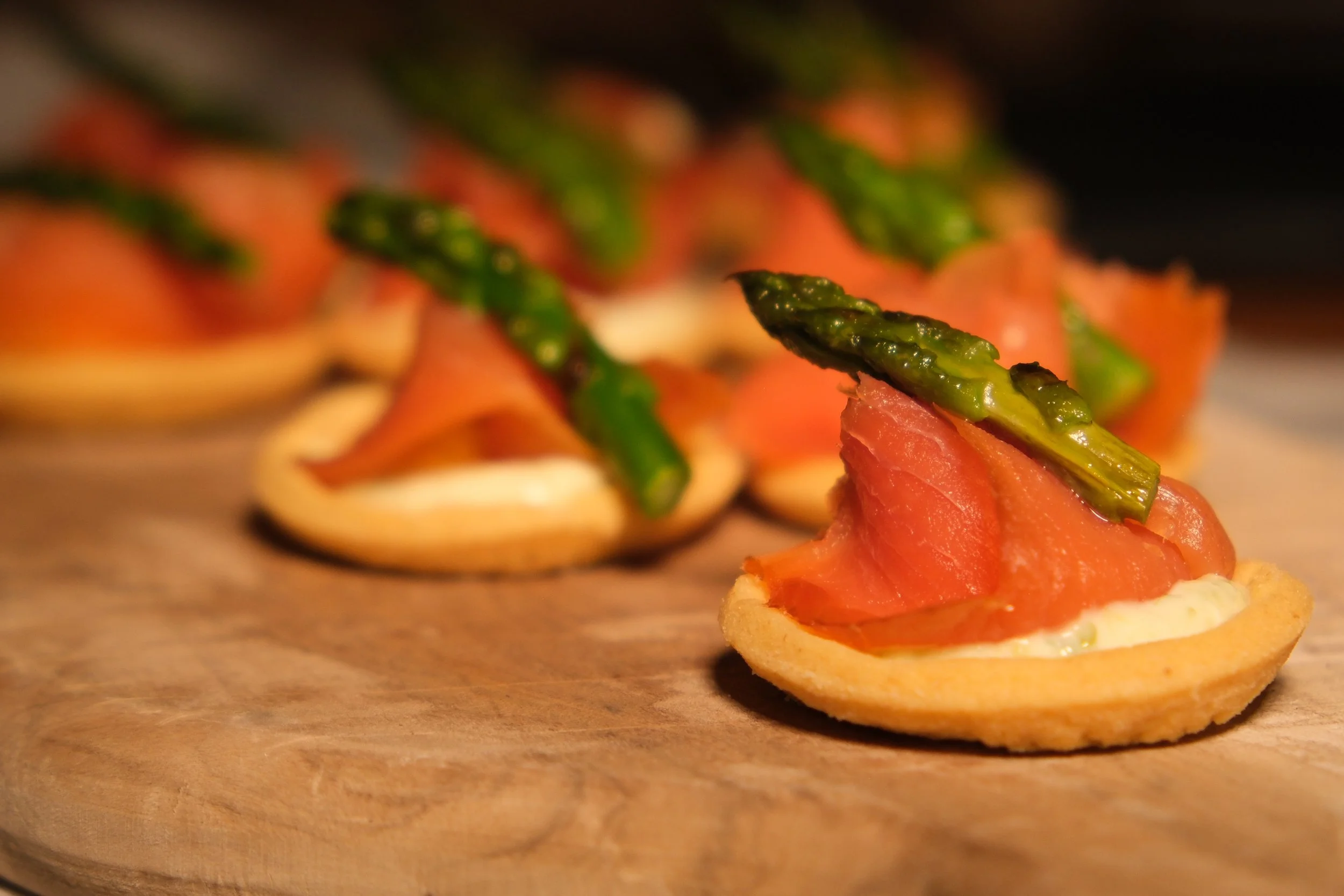 Appetizer with smoked salmon, green asparagus, and creamy white spread on a round cracker