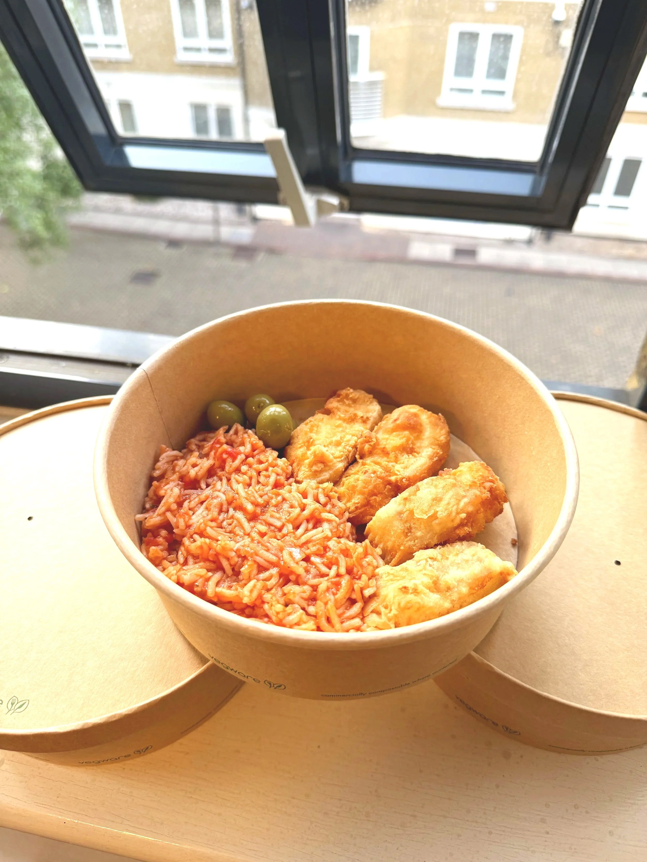 Three boxed and ready portions of fish fillets, with tomato rice and green olives. Couple of Natas Catering, Film and TV television catering. Hot boxing, on site location catering, and craft services.