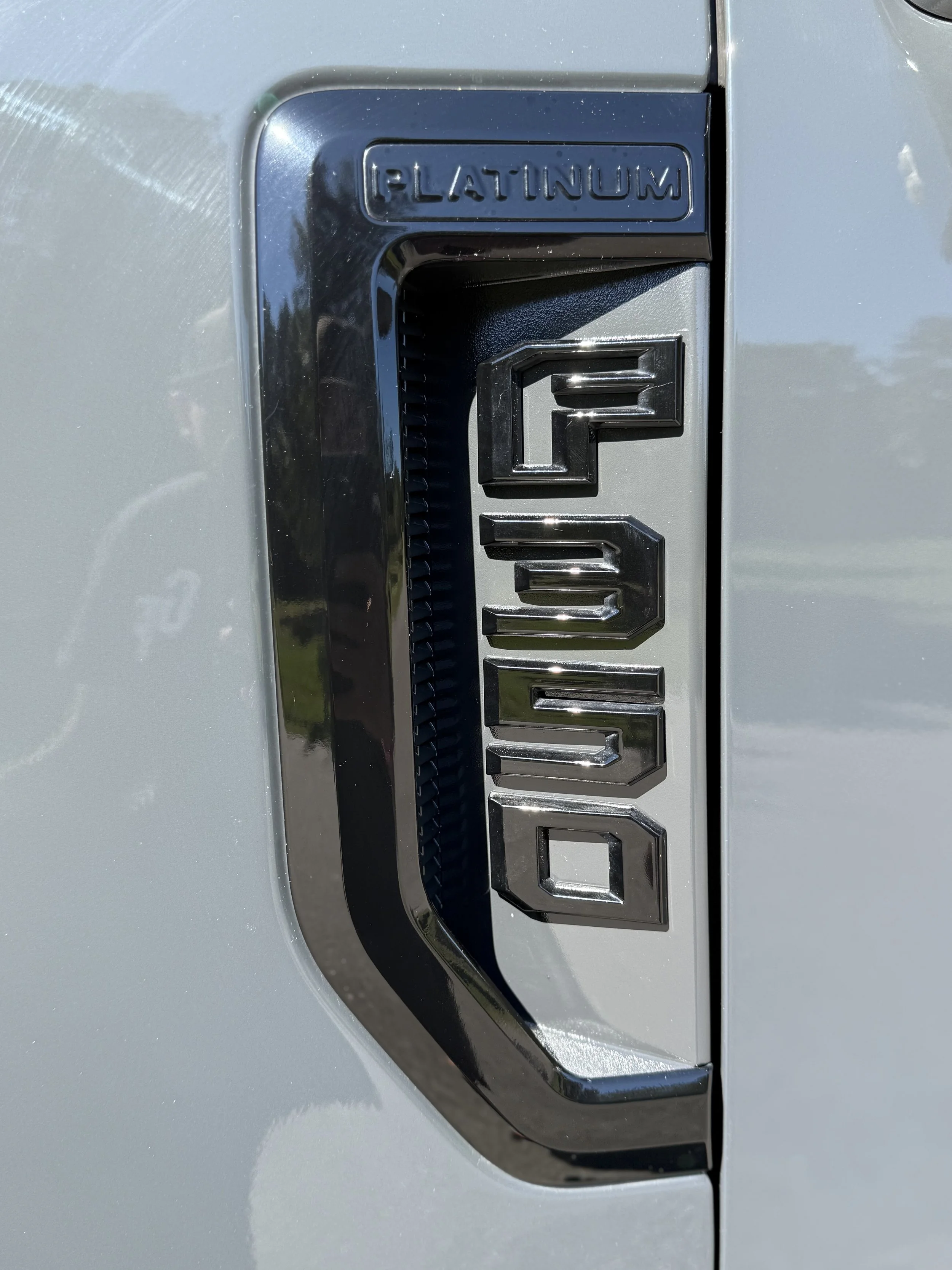 Close-up of a silver Ford F-150 badge on a pickup truck, with the word 'PLATINUM' embossed above.