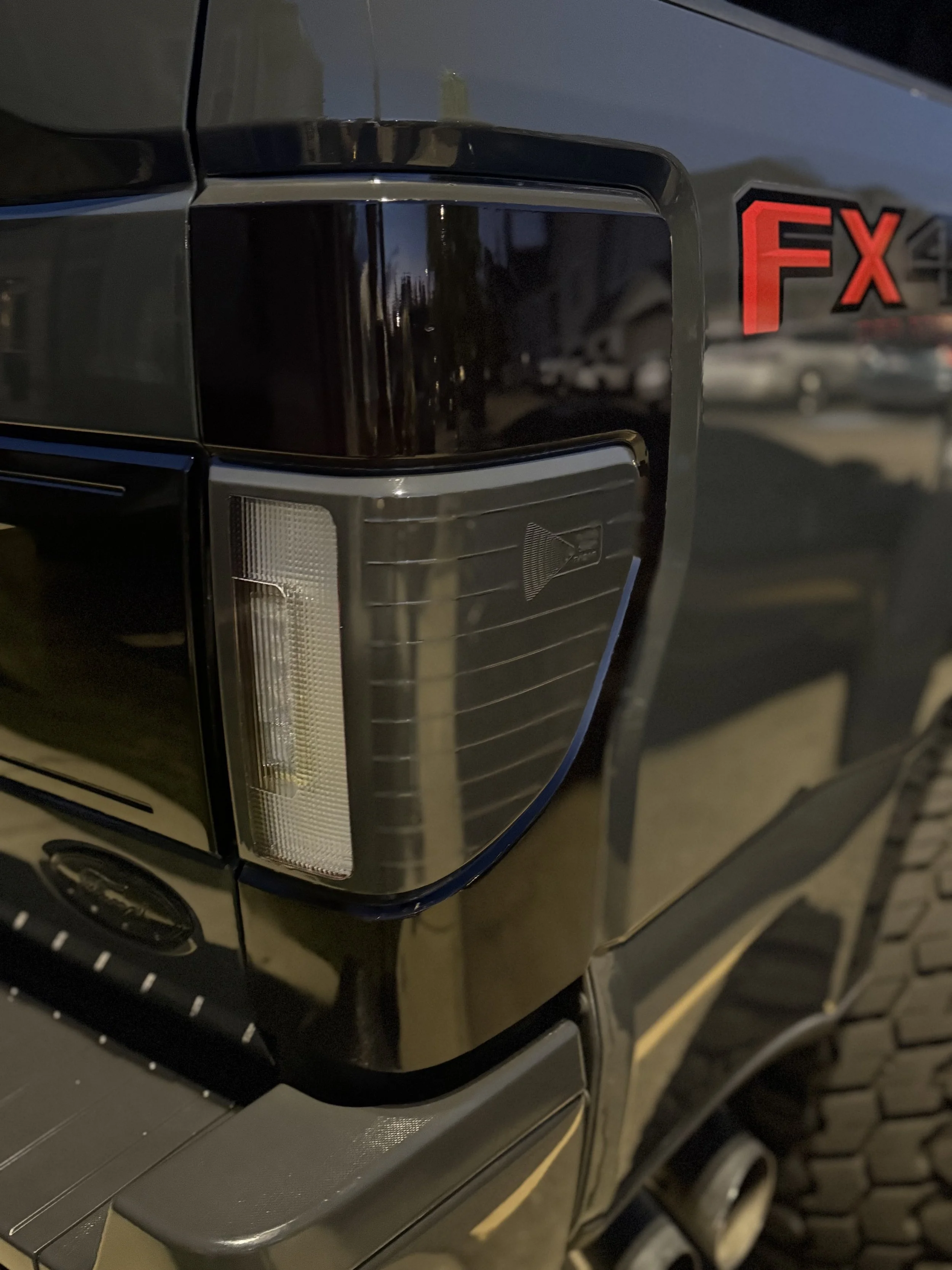 Close-up of the rear side of a black vehicle with a red 'FX' badge.