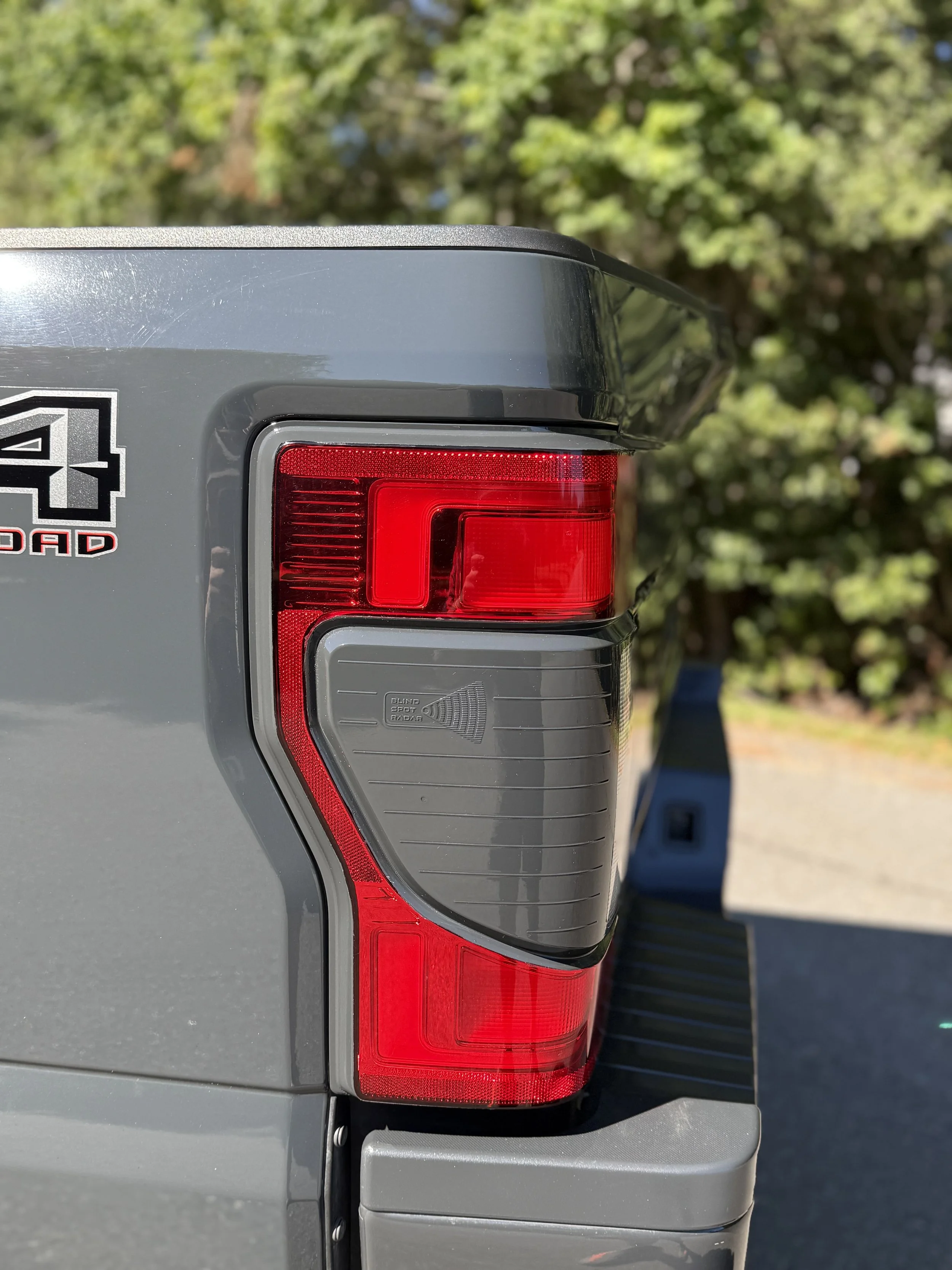Close-up of the rear tail light of a gray pickup truck with a '4x4 Off-Road' decal.