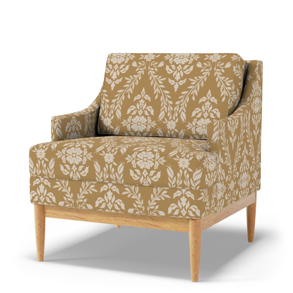An ochre armchair with floral and leaf patterns in white, wooden legs, and rounded armrests.
