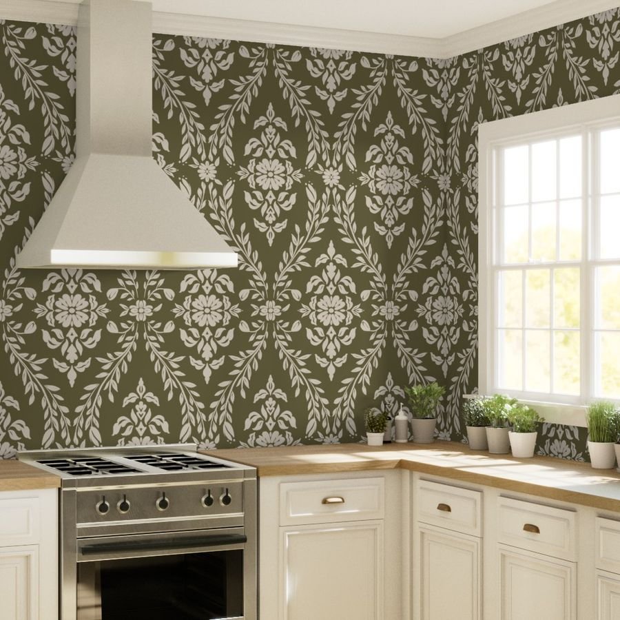 Kitchen with patterned olive green and white wallpaper, white cabinets, wooden countertop, stainless steel stove, and potted plants near a window.