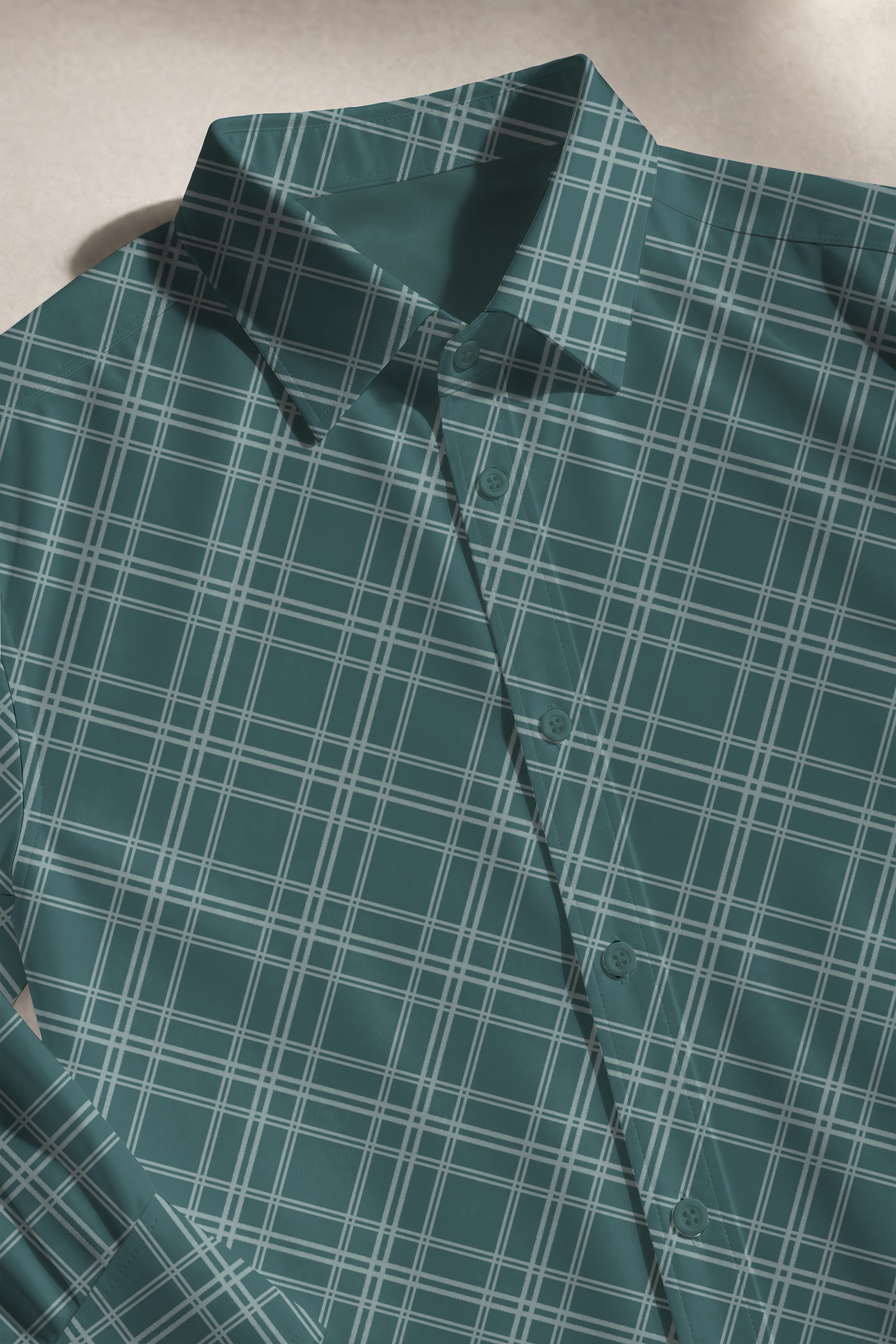 Teal button-up shirt with slate blue plaid pattern laid flat on a surface.