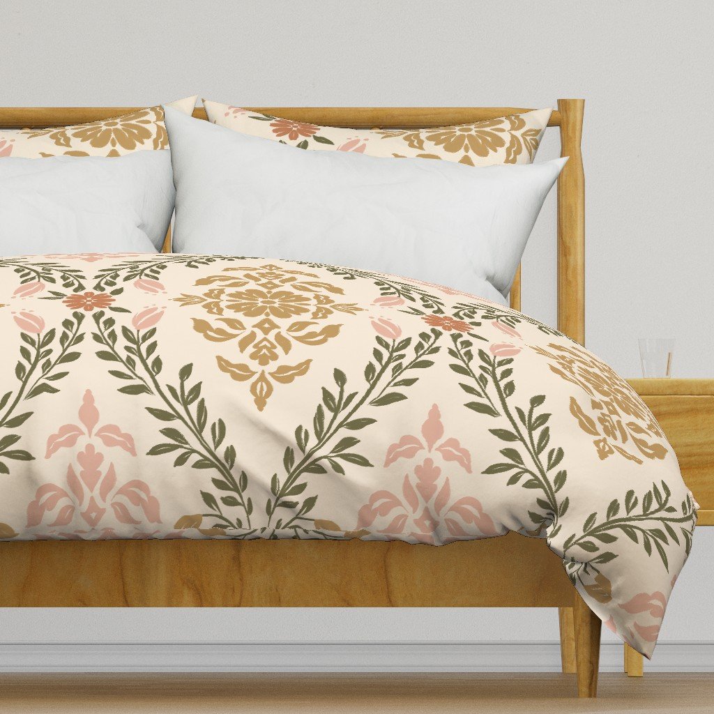 Close-up of a wooden bed with a multi-colored floral damask patterned duvet cover in ochre, rose, olive, and terracotta on a cream backgound, with several white and floral pillows, set against a plain wall.