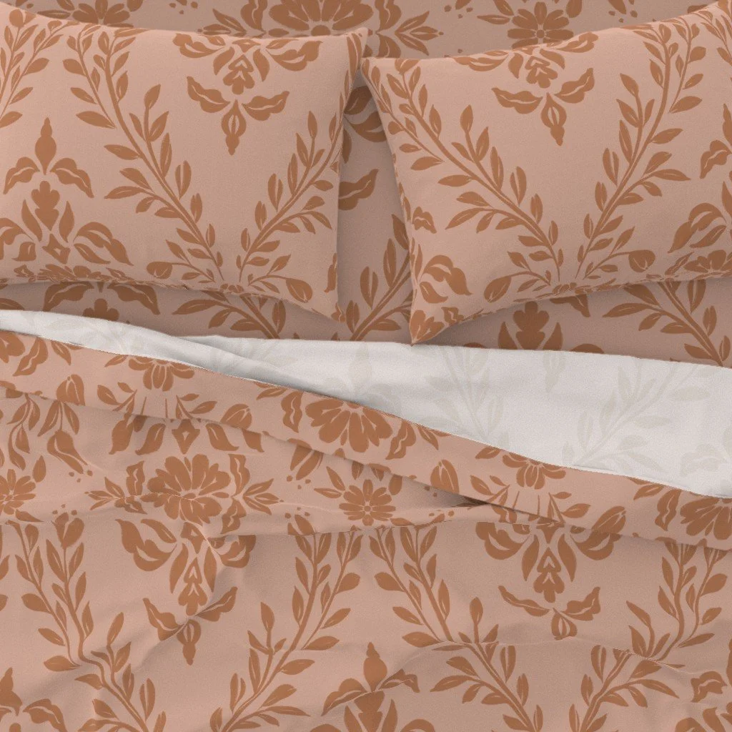 Close-up of a bed with rose and terracotta floral damask-patterned pillowcases and bedding.