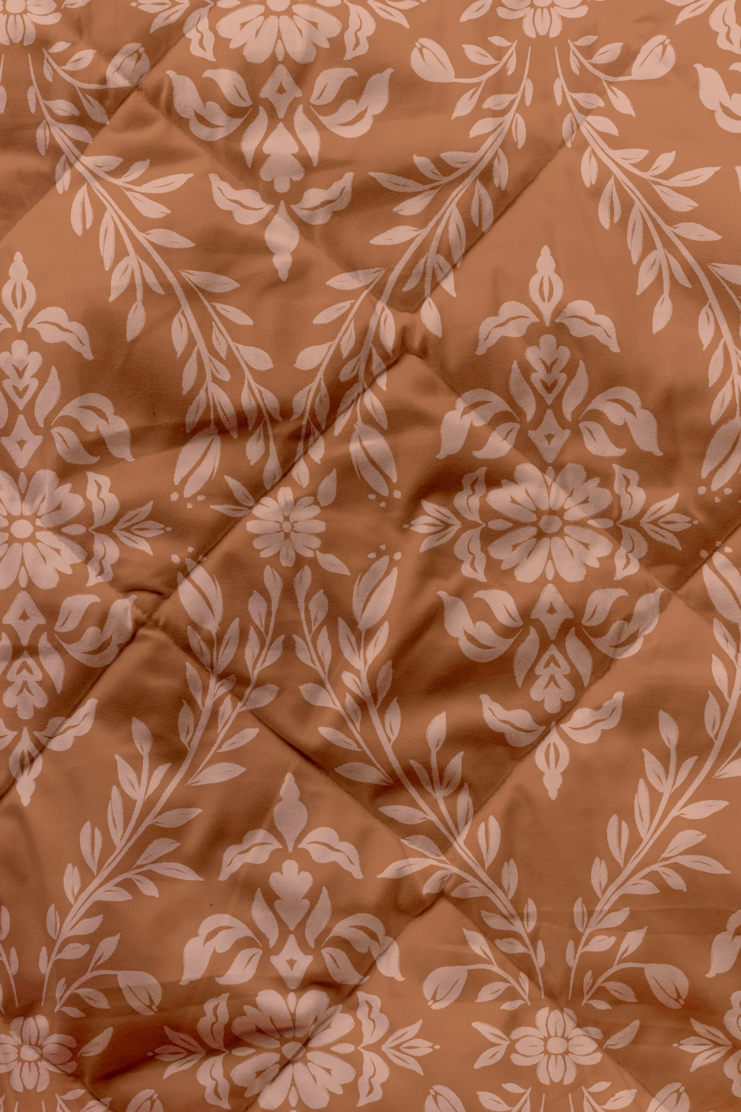 A close-up of a quilted fabric with a terracotta background and rose pink floral damask pattern.