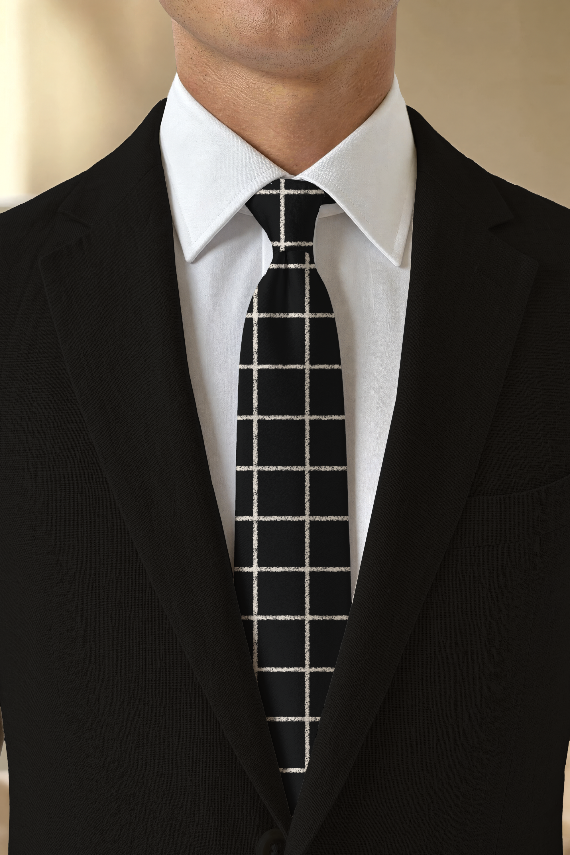 Close-up of a man wearing a black suit, white dress shirt, and a black tie with white windowpane plaid pattern.