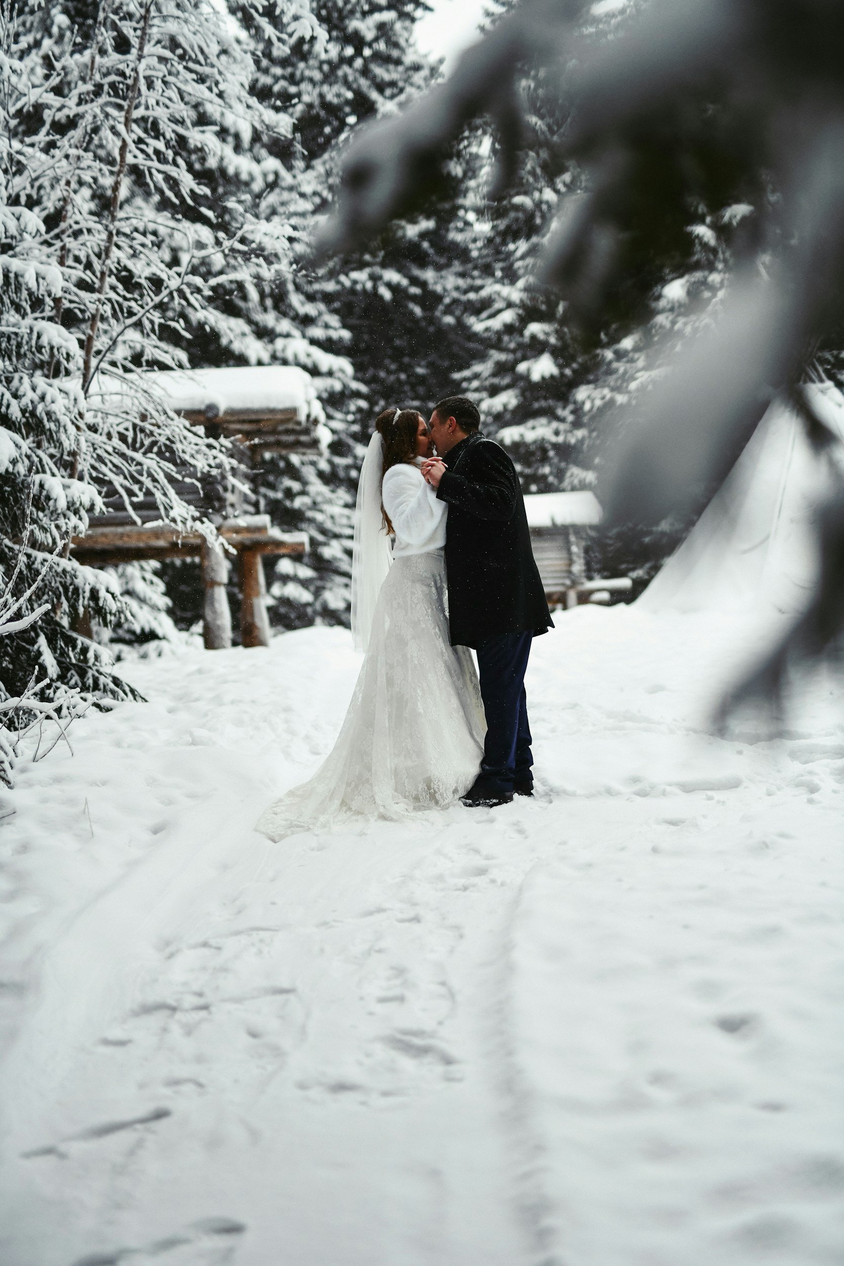 Bride and groom kissing outside in the snow.
