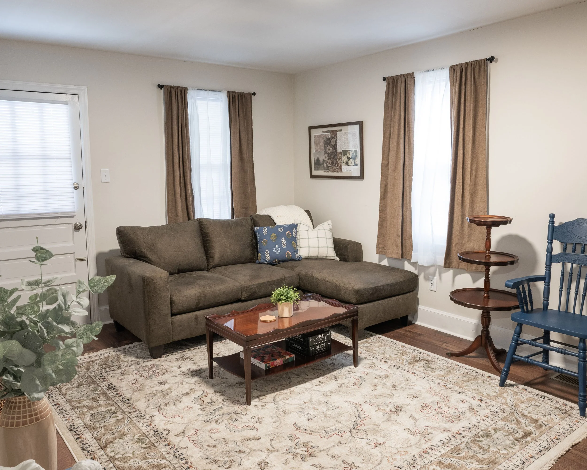 Living room with a brown sofa, coffee table, and blue rocking chair on an ornate rug.
