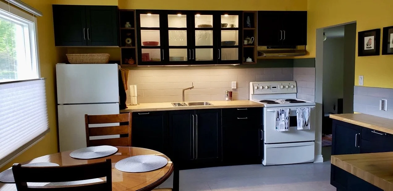 Small kitchen utilizing more appropriate prefab cabinets, new backsplash tile, new flooring and a more open feel connected to the living room.