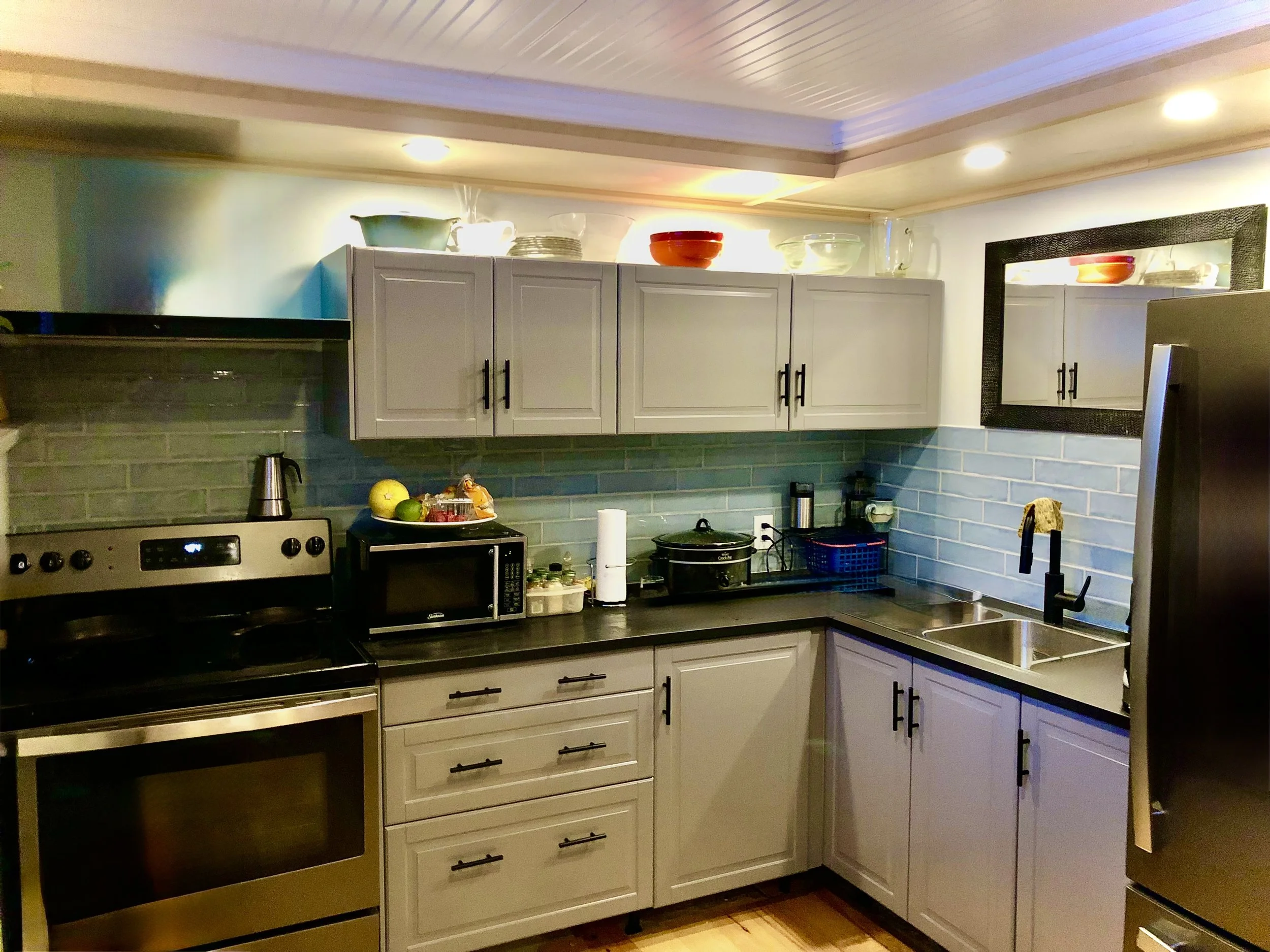 Complete  new kitchen in basement suite utilizing prefab cabinets. New backsplash tile throughout with custom dropped chase for lighting and hiding utilities. Engineered hardwood flooring approved for basement flooring use.