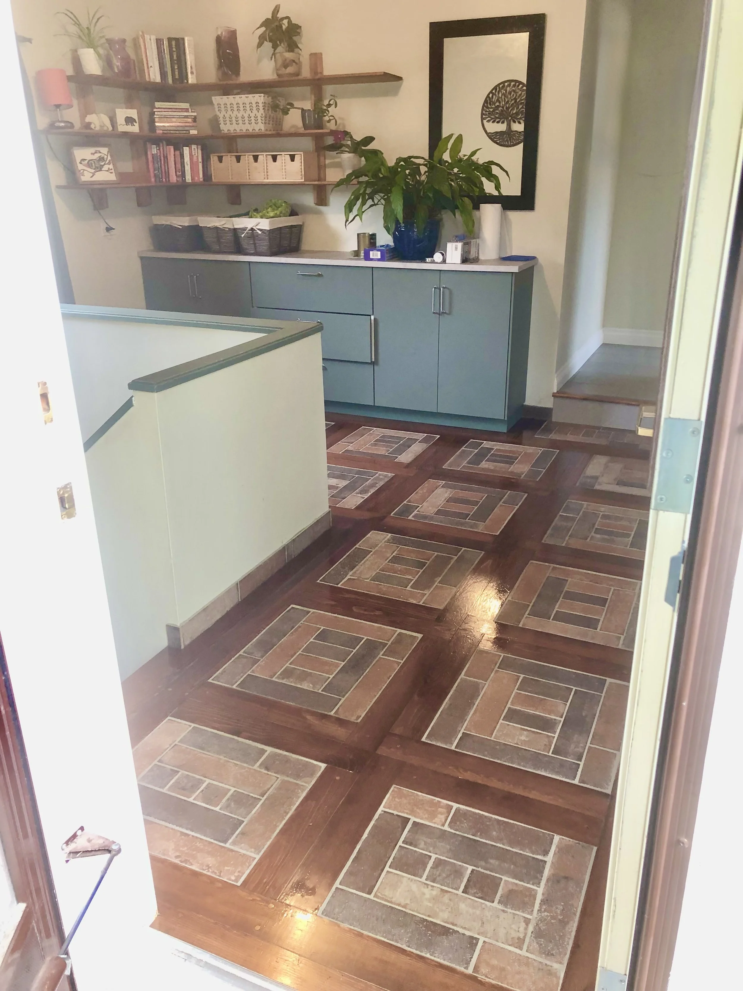 Entryway showing all three new elements together: custom floor in wood and tile, prefab cabinets, custom corner shelf unit.