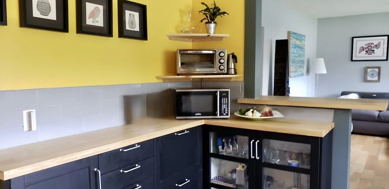 Small kitchen with new orientation of cabinets utilizing both narrow and full-sized prefab construction to maximize space. Open wall and passage between kitchen and living room to create a grand room feel. 