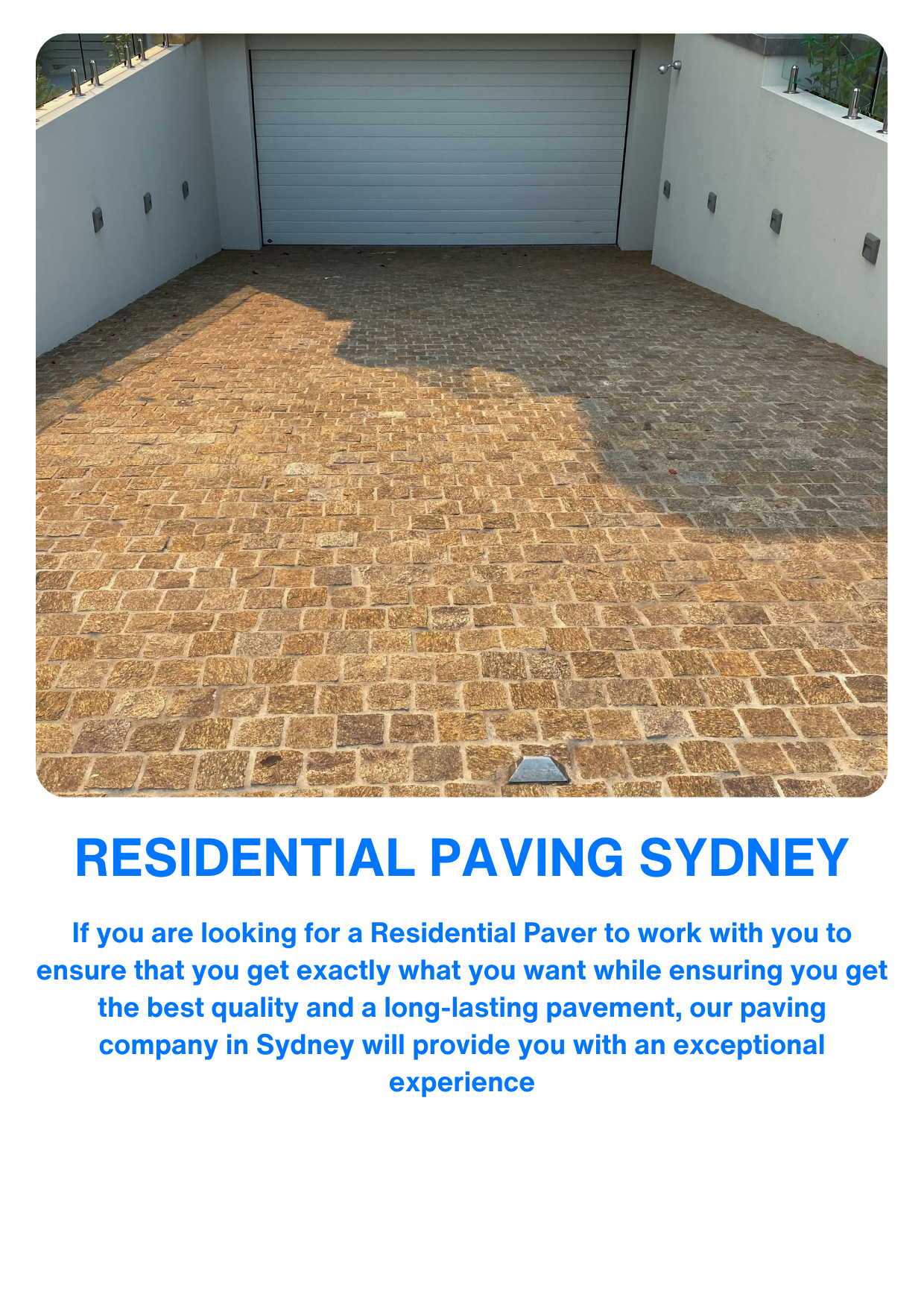 A paved driveway with brick pavers leading to a gray garage door, surrounded by white walls with small exterior lights.