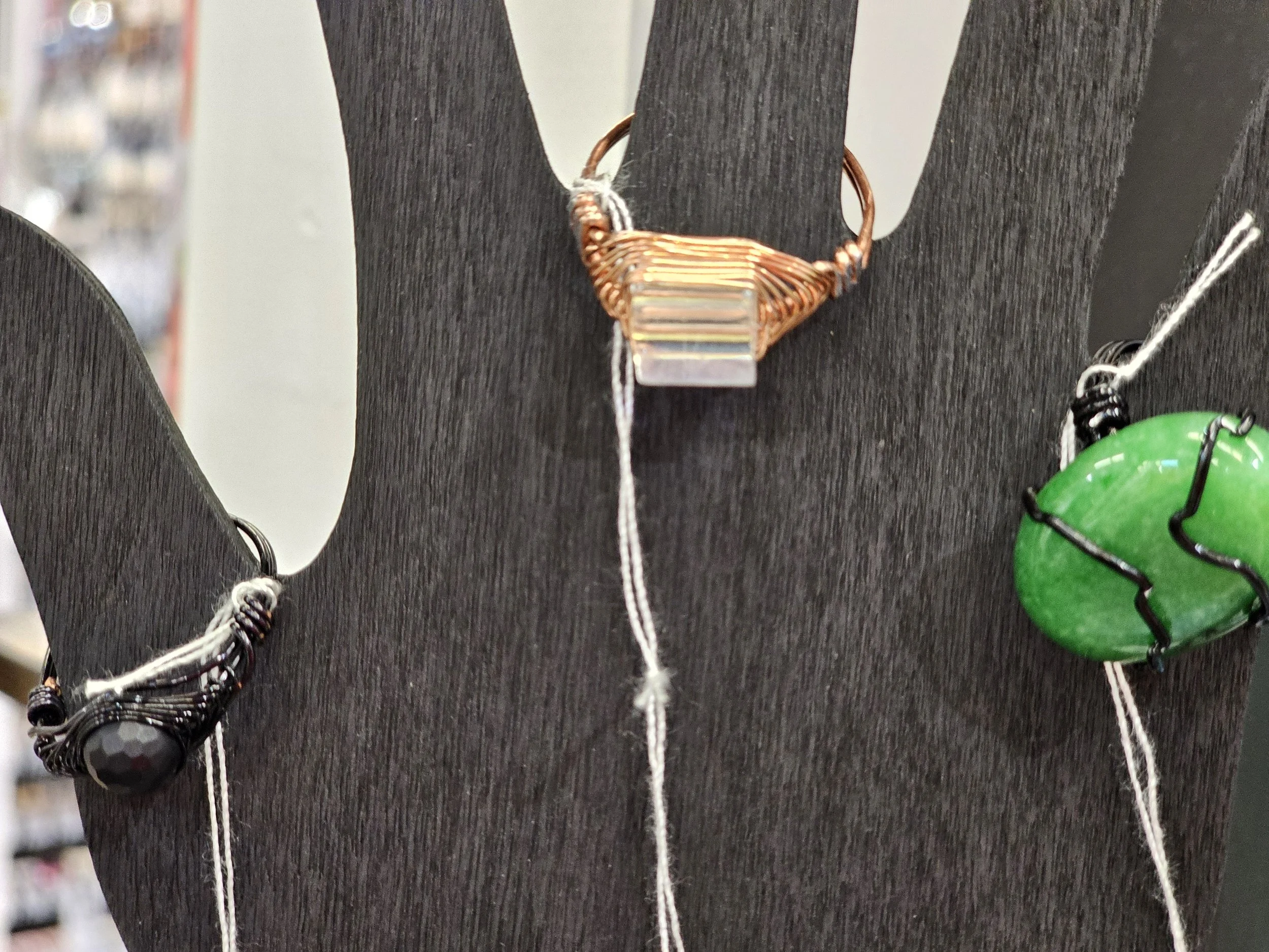 Wire wrapped rings displayed on a black wooden hand stand.
