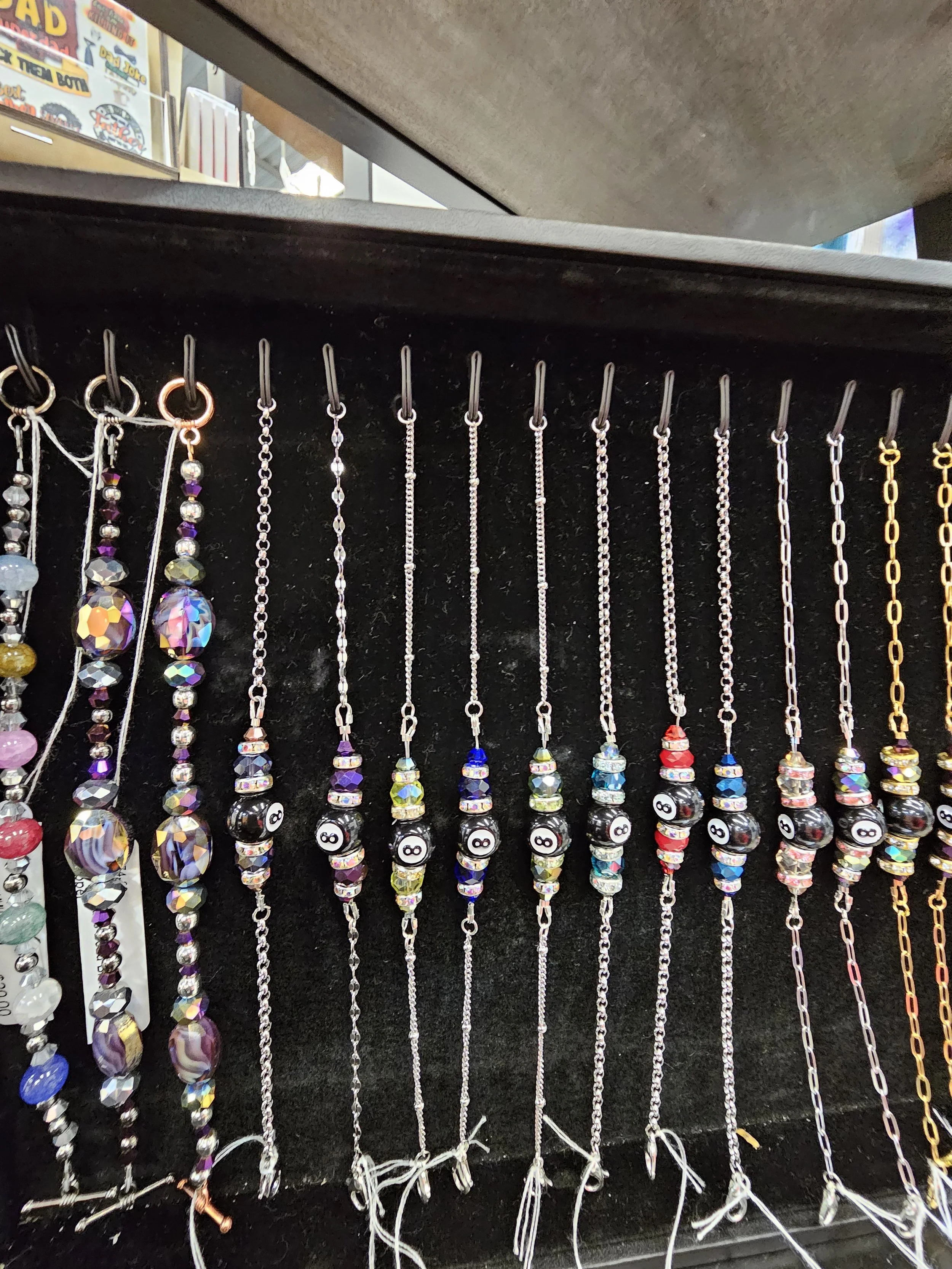 Collection of beaded bracelets with 8-ball beads on display.