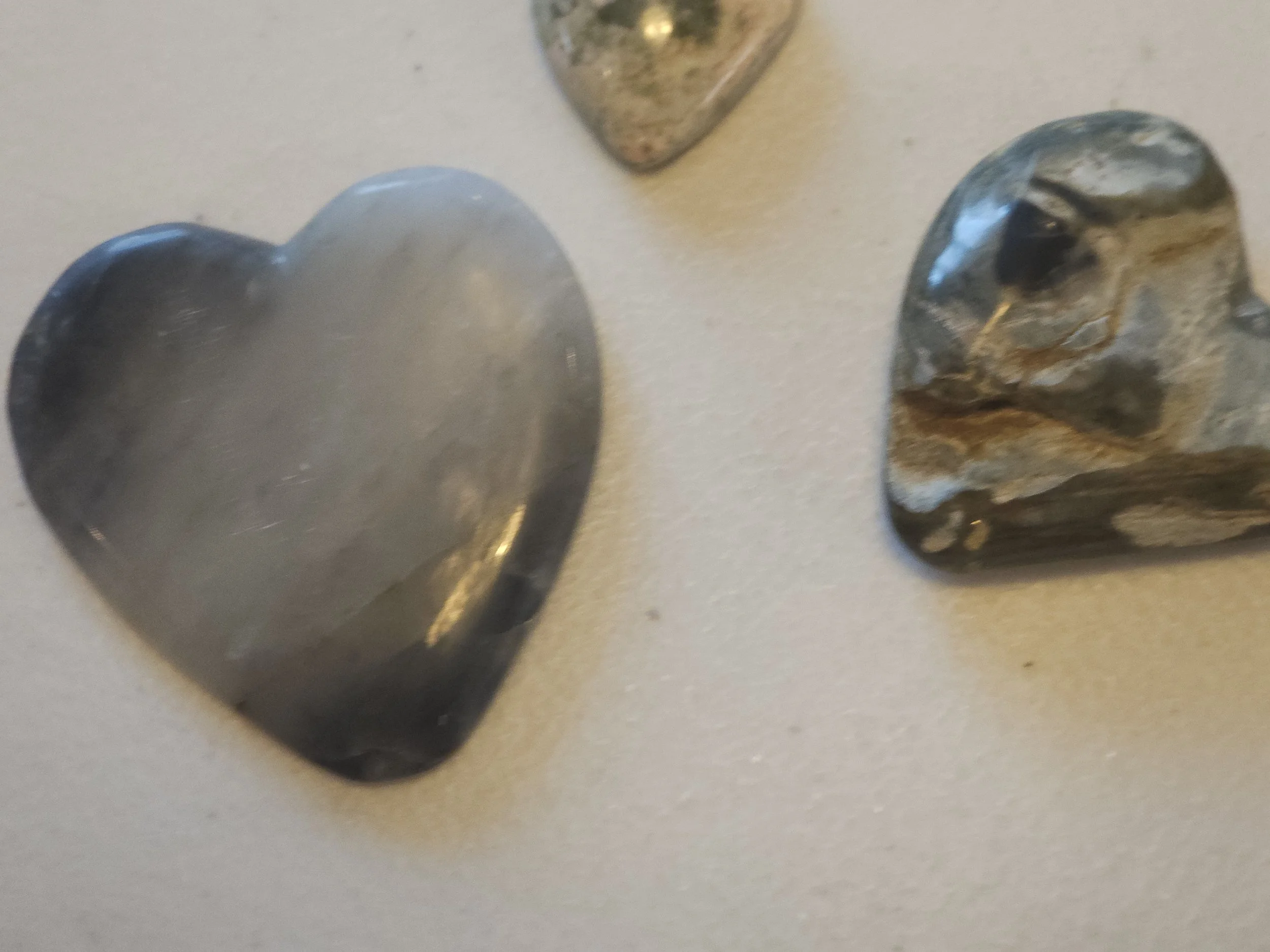 Three heart-shaped and irregularly shaped metallic hand-cut stones ready for jewelry.