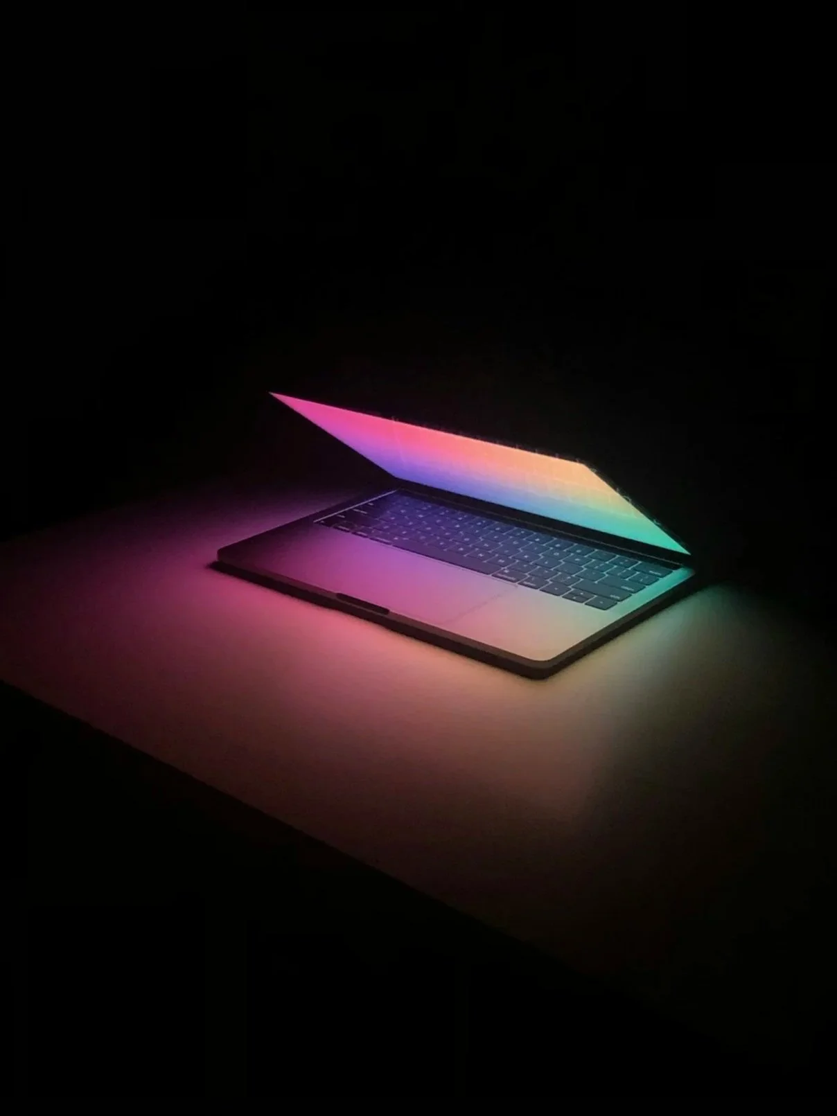 Neon glowing laptop on a black table and black