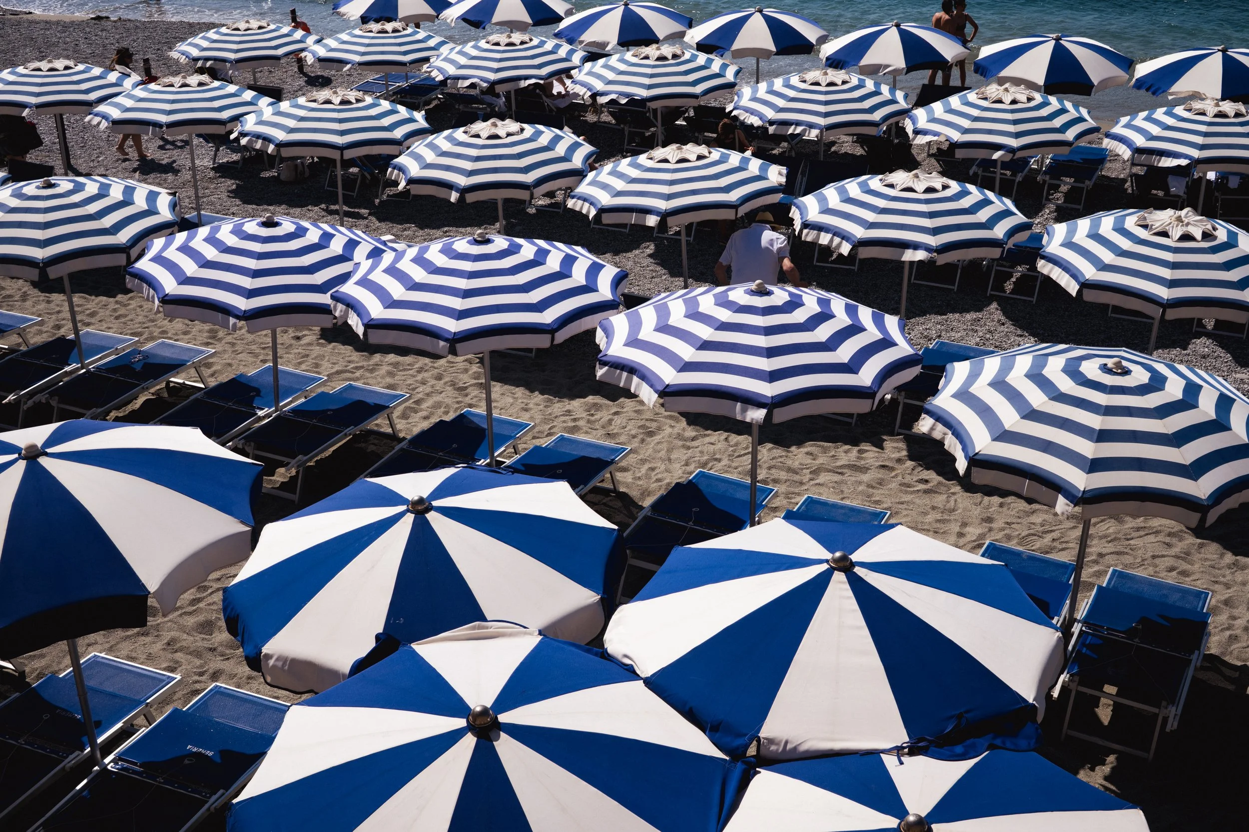 'Lines in the Sand' Lines of blue and white umbrellas at the beach 
