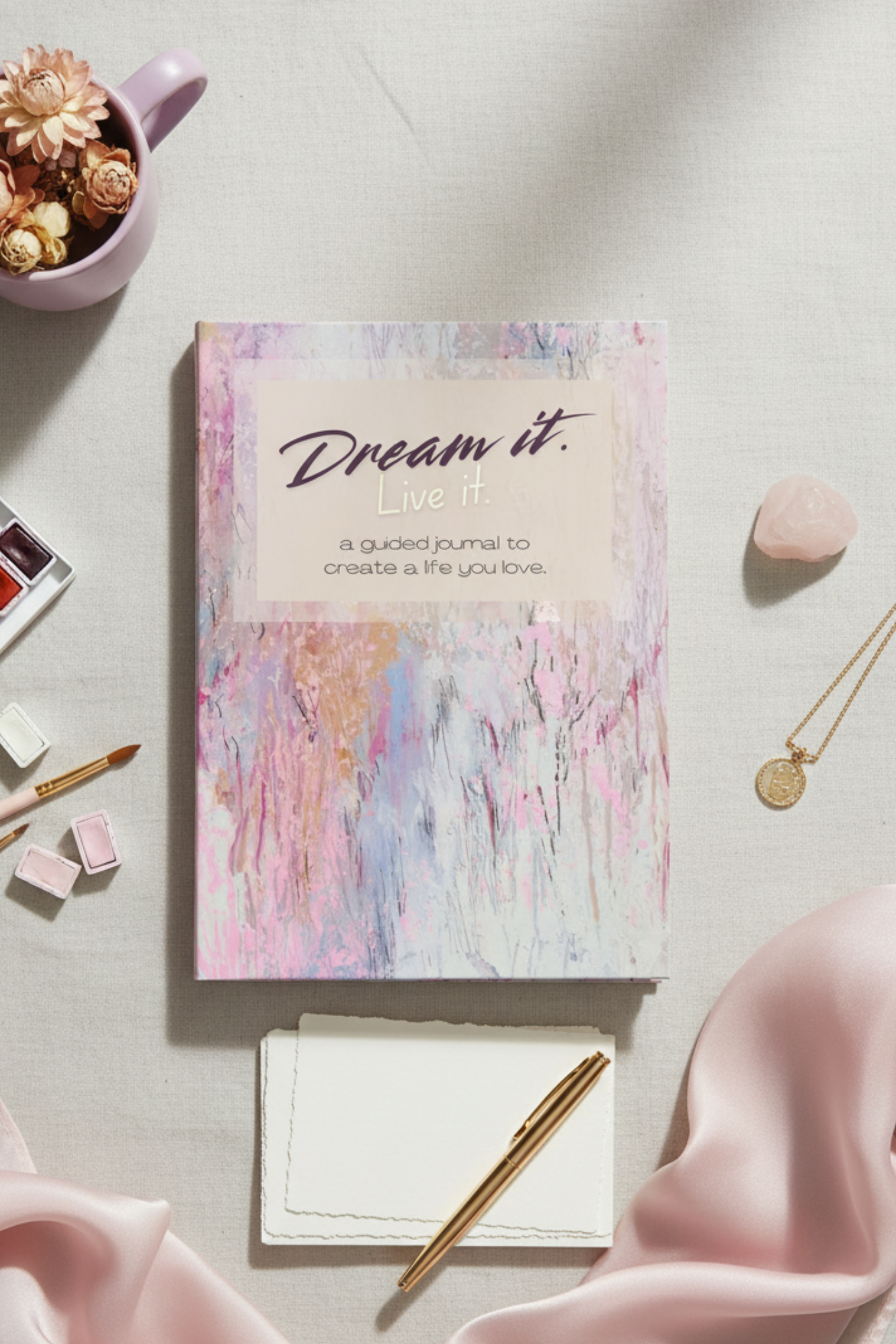 A motivational journal cover with abstract pastel background, featuring the quote 'Dream it. Live it.' and the subtitle 'a guided journal to create a life you love.'