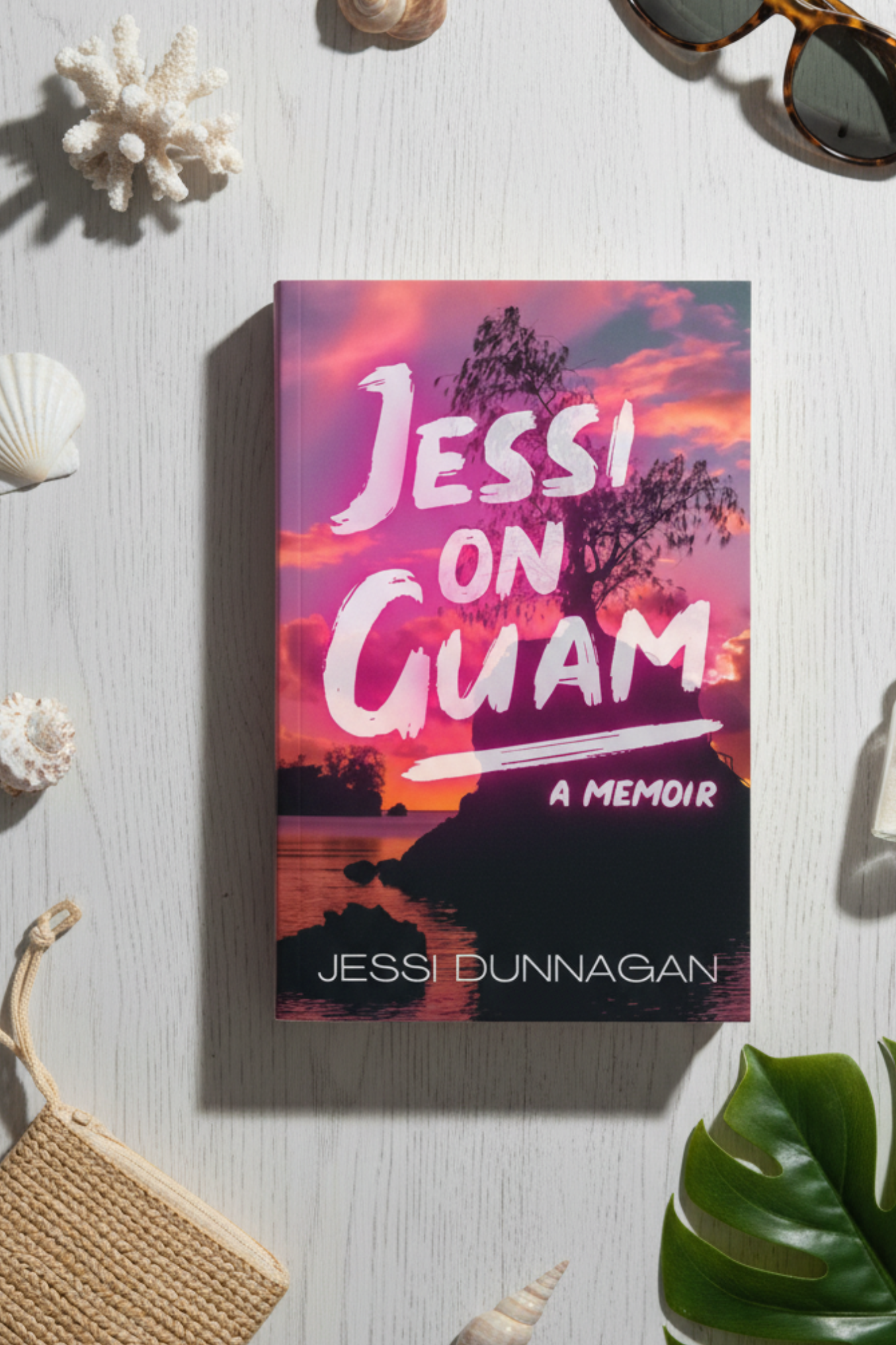Book cover titled 'Jessi on Guam: A Memoir' with a sunset over the ocean, silhouette of a tree on a small island, and vibrant pink and orange skies.