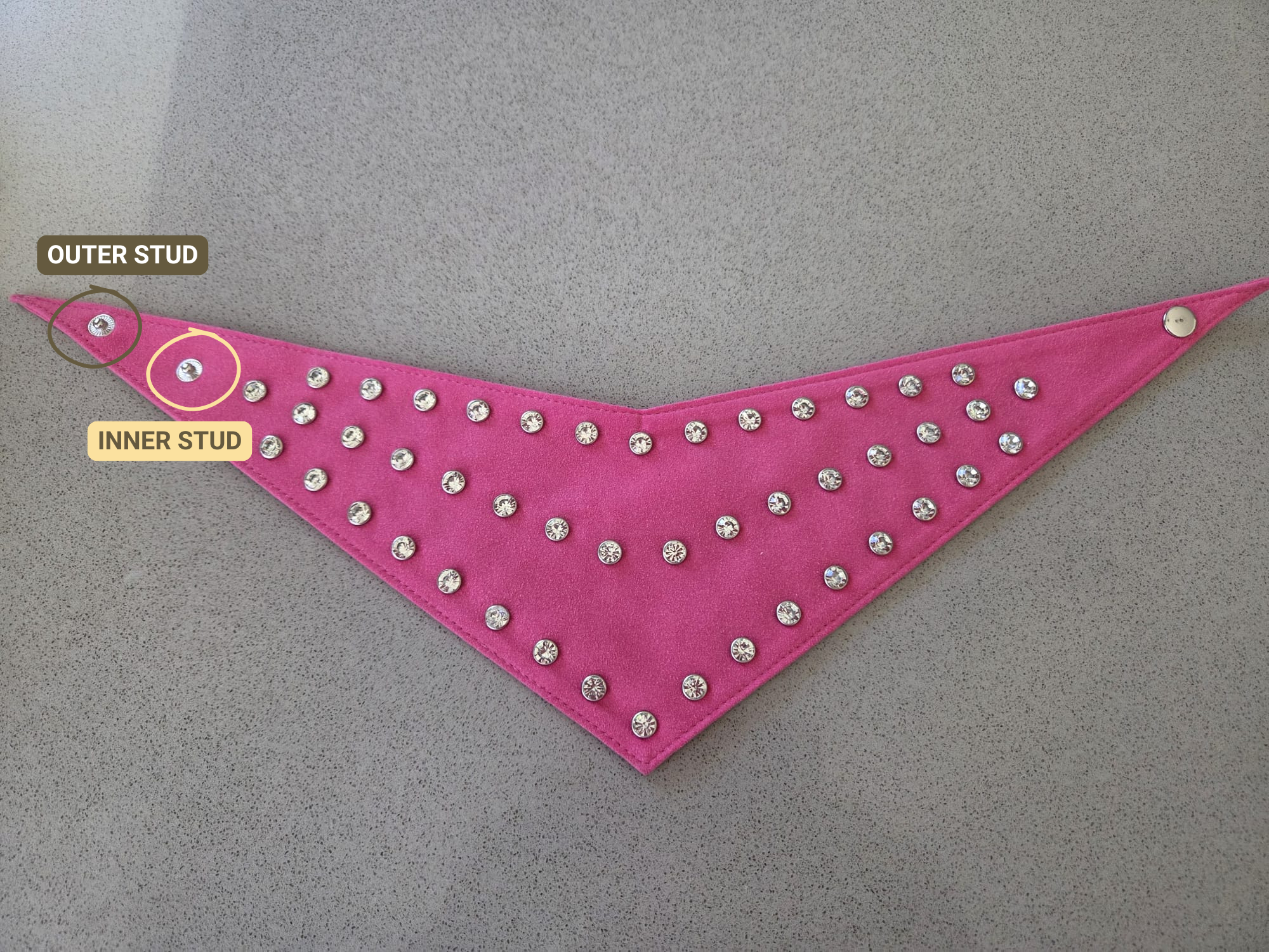Small pink suede diamante dog bandana laid flat, with text pointing out to the outer and inner studs.