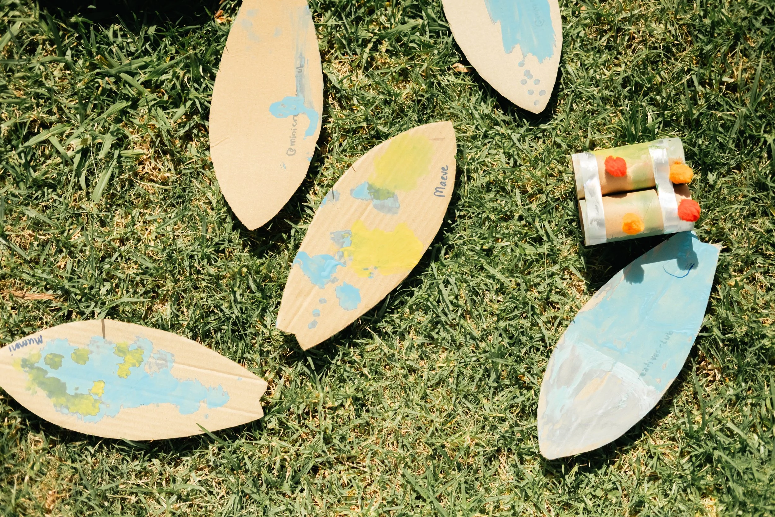 Colorful paper leaves and a small foam rocket craft with pom-poms on grass