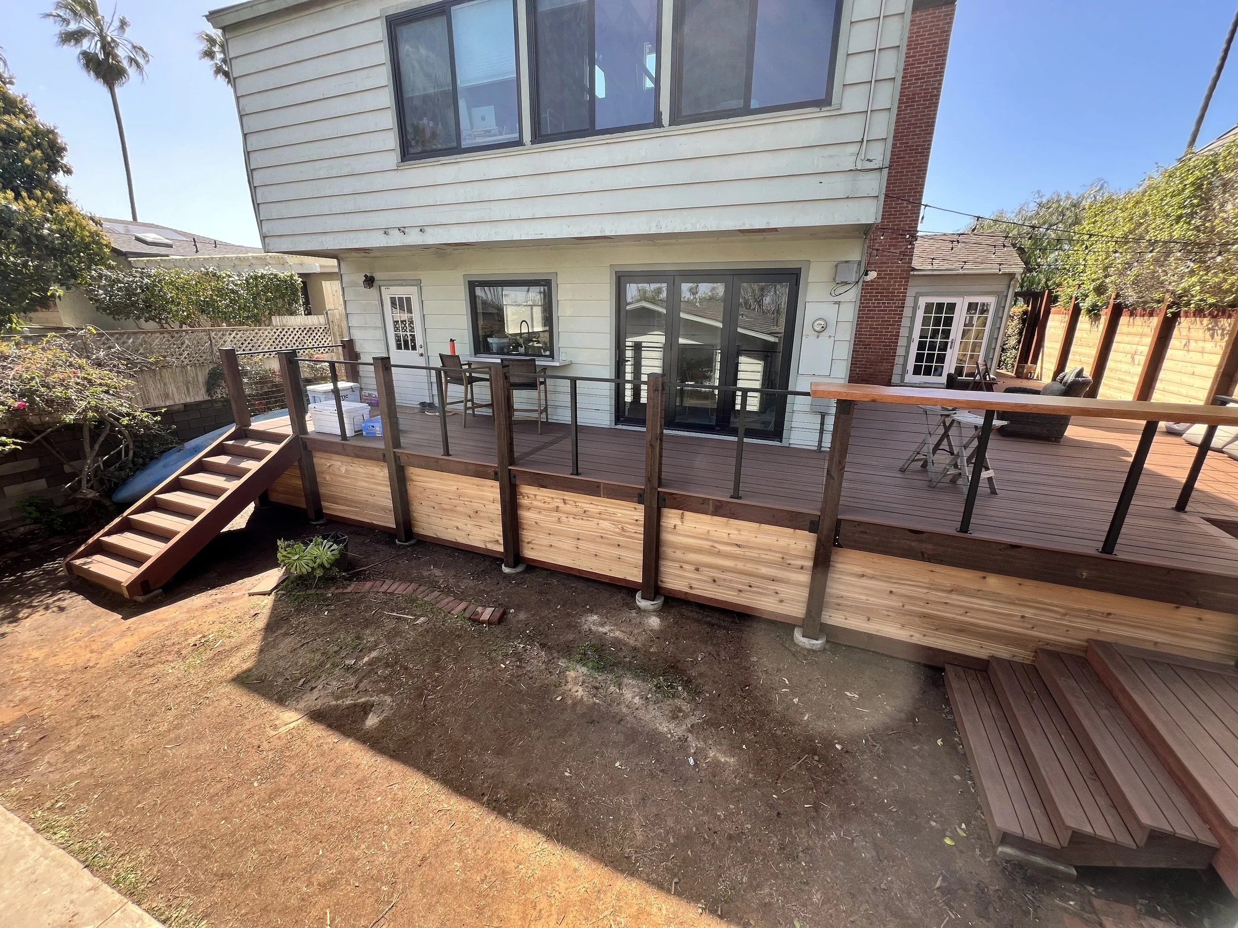 Massive TimberTech deck installation in Ocean Beach featuring Mahogany PVC deck boards, multiple staircases and a Cedar tongue and groove privacy fence. 