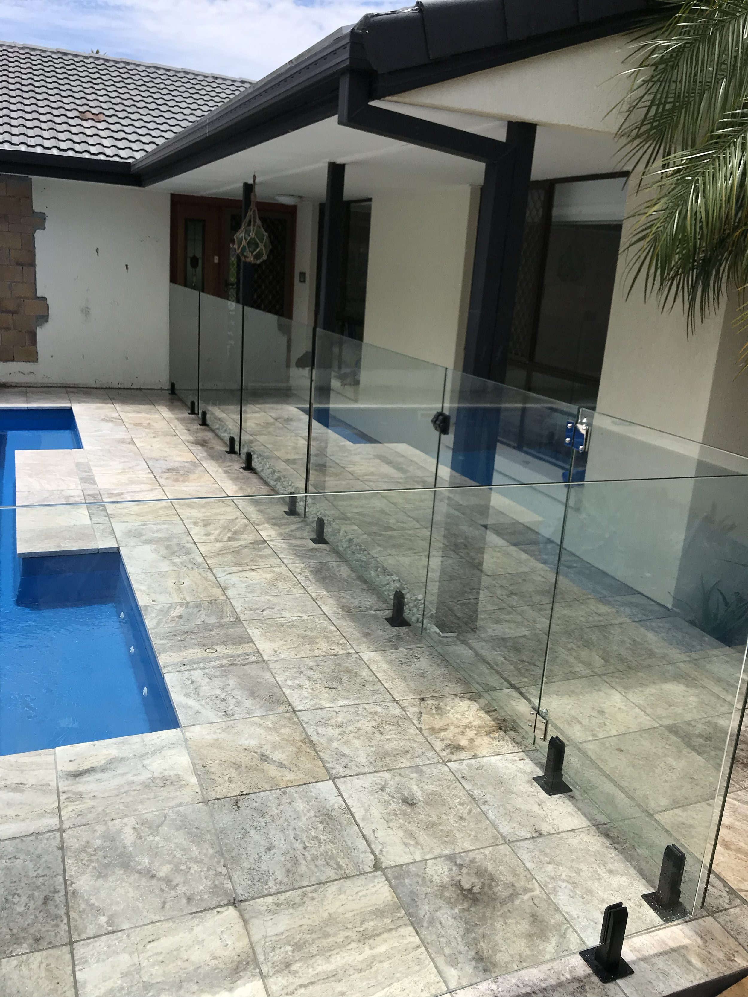 Frameless glass pool fence on tiled patio – Coastline Glass install