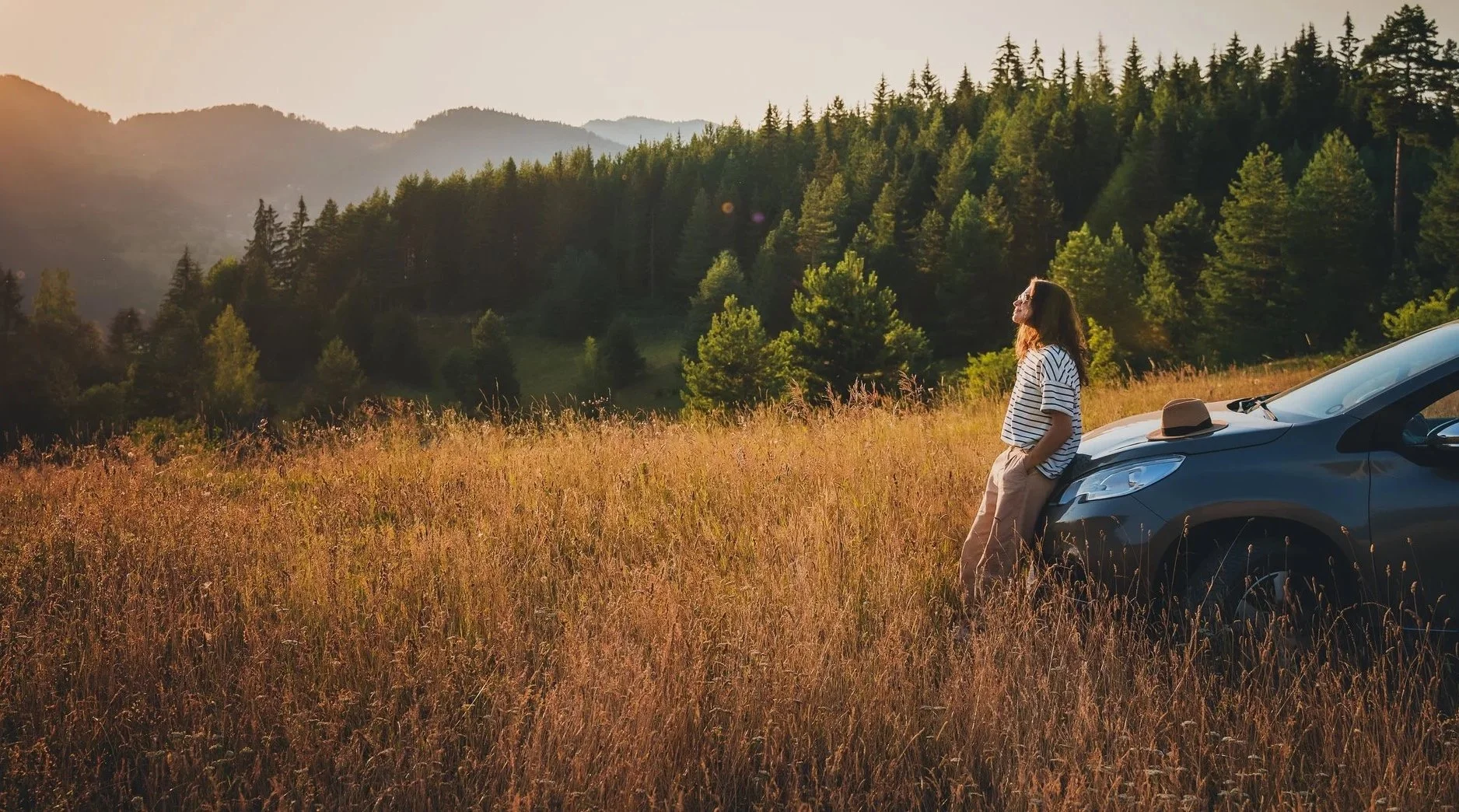 Scenic mountain landscape with snow-capped peaks in the background and a modern building on the rolling hills in the foreground.