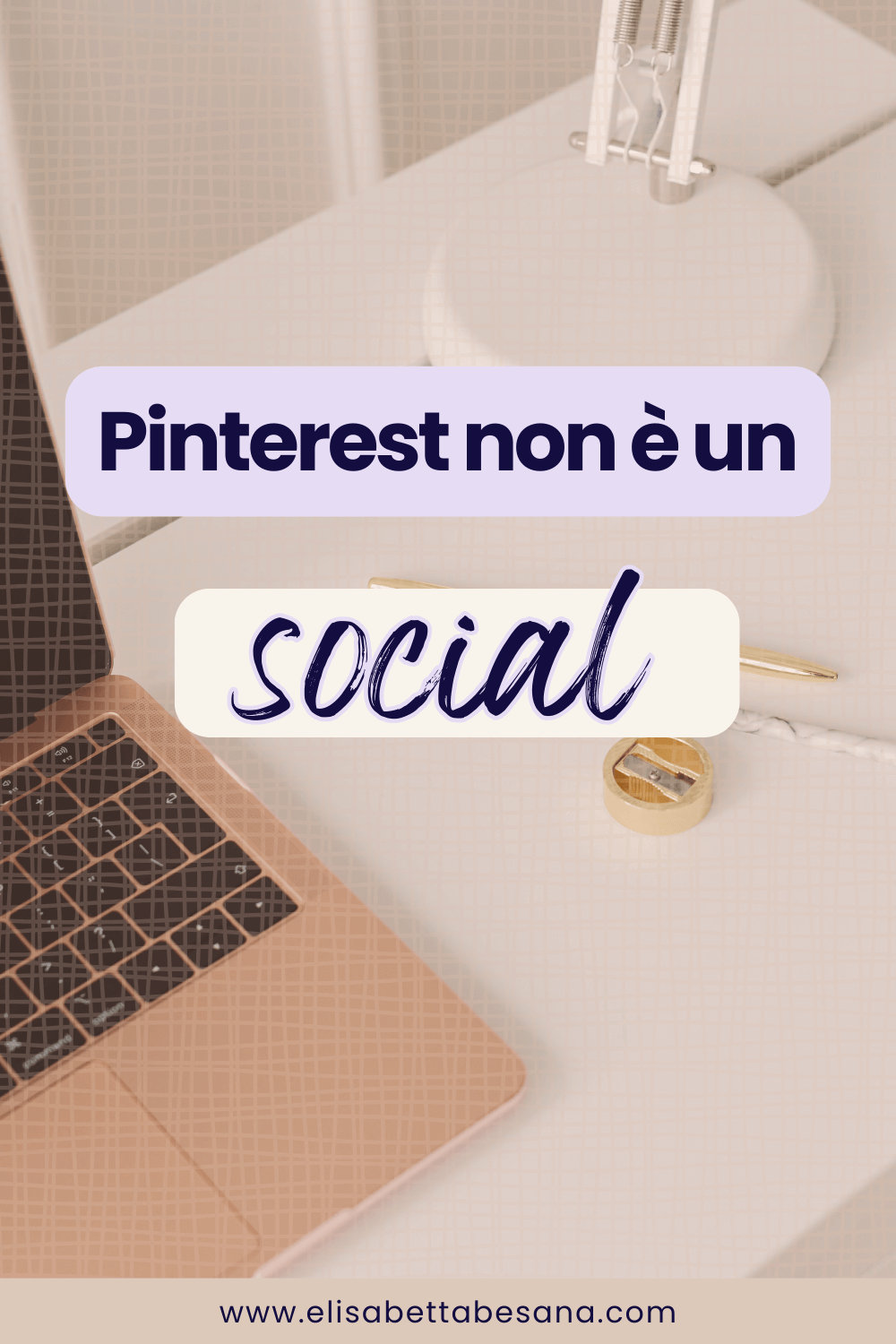 aptop rosa aperto su tavolo bianco, si intravede la base di una lampada da scrivania bianca