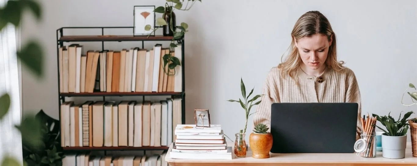 giovane donna seduta al pc in un ambiente ordinato e curato. Scopri i segreti della Pinterest SEO per attrarre clienti.
