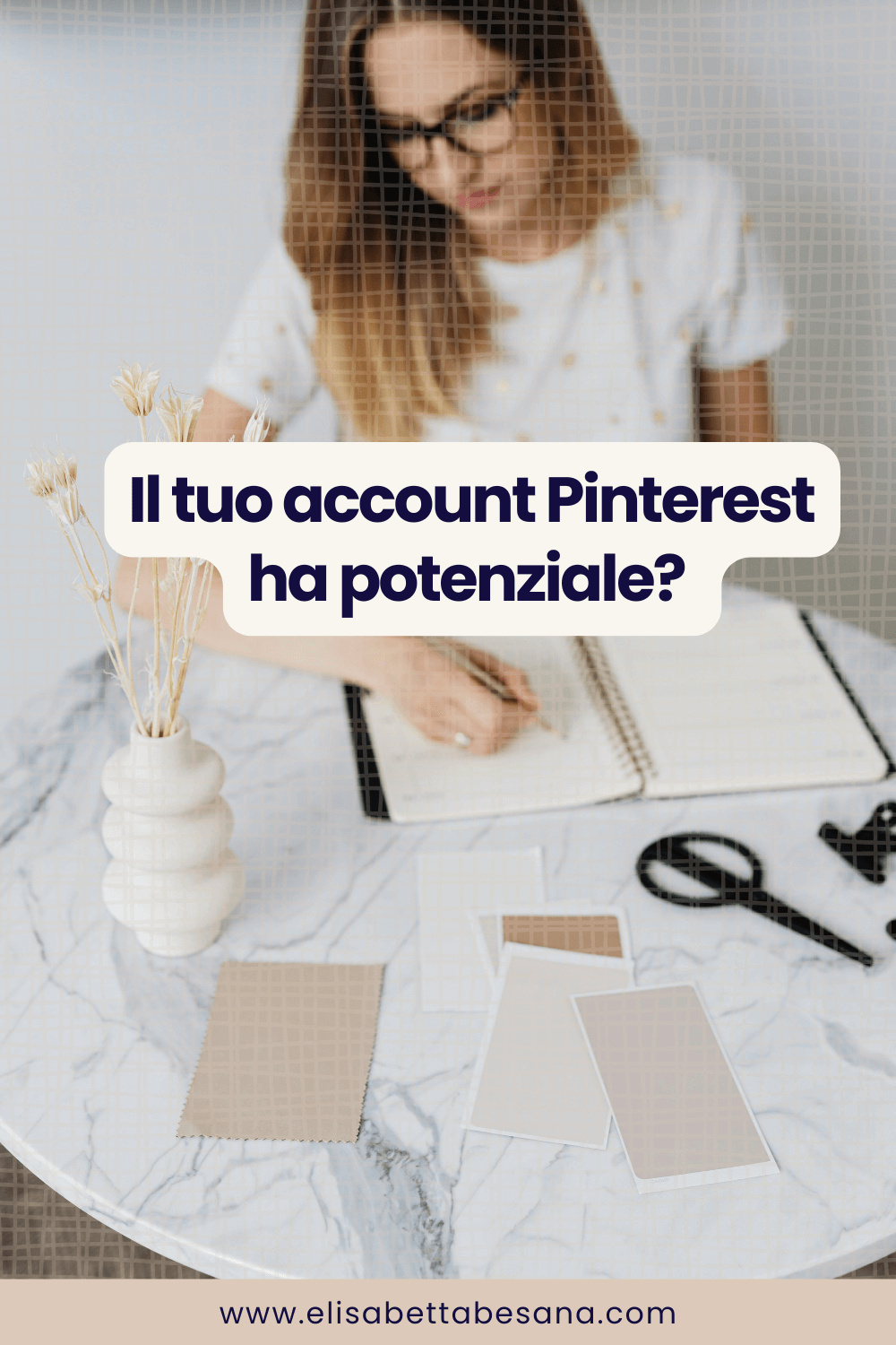 giovane donna intenta a scrivere su un quaderno seduta ad un tavolo di marmo bianco con poggiati sopra campioni di palette