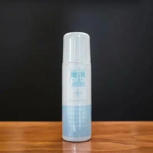 A white and blue aerosol can with a white cap on a wooden surface against a black background.