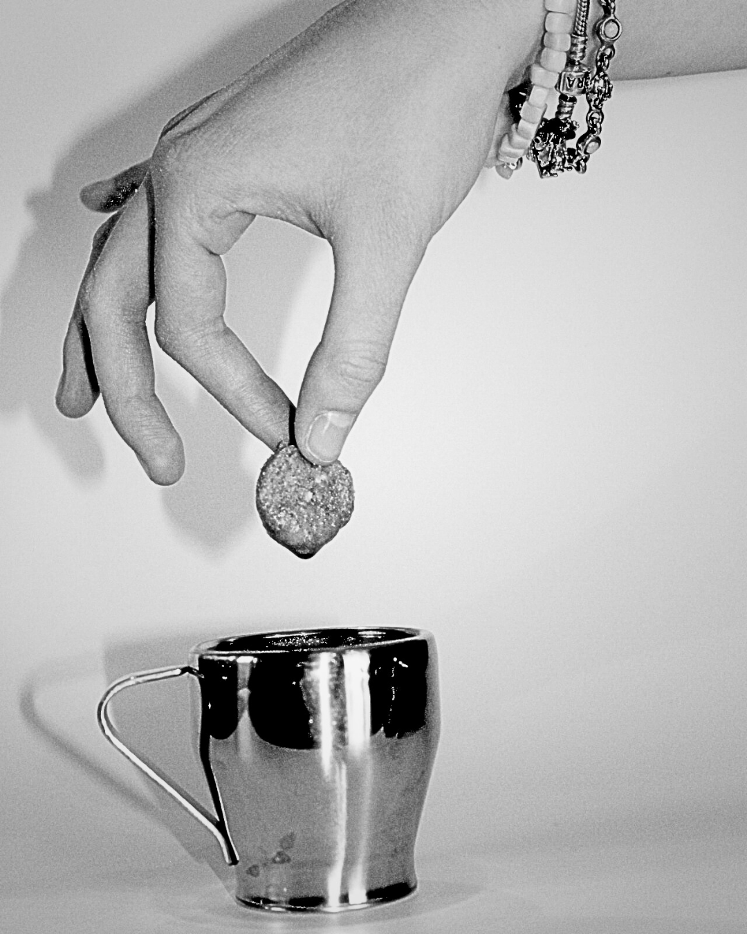 Photo en noir et blanc d'une main qui trempe un biscuit dans un café