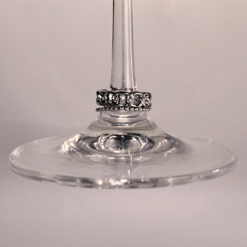 Une bague en argent enfilée sur le pied d'une coupe de vin