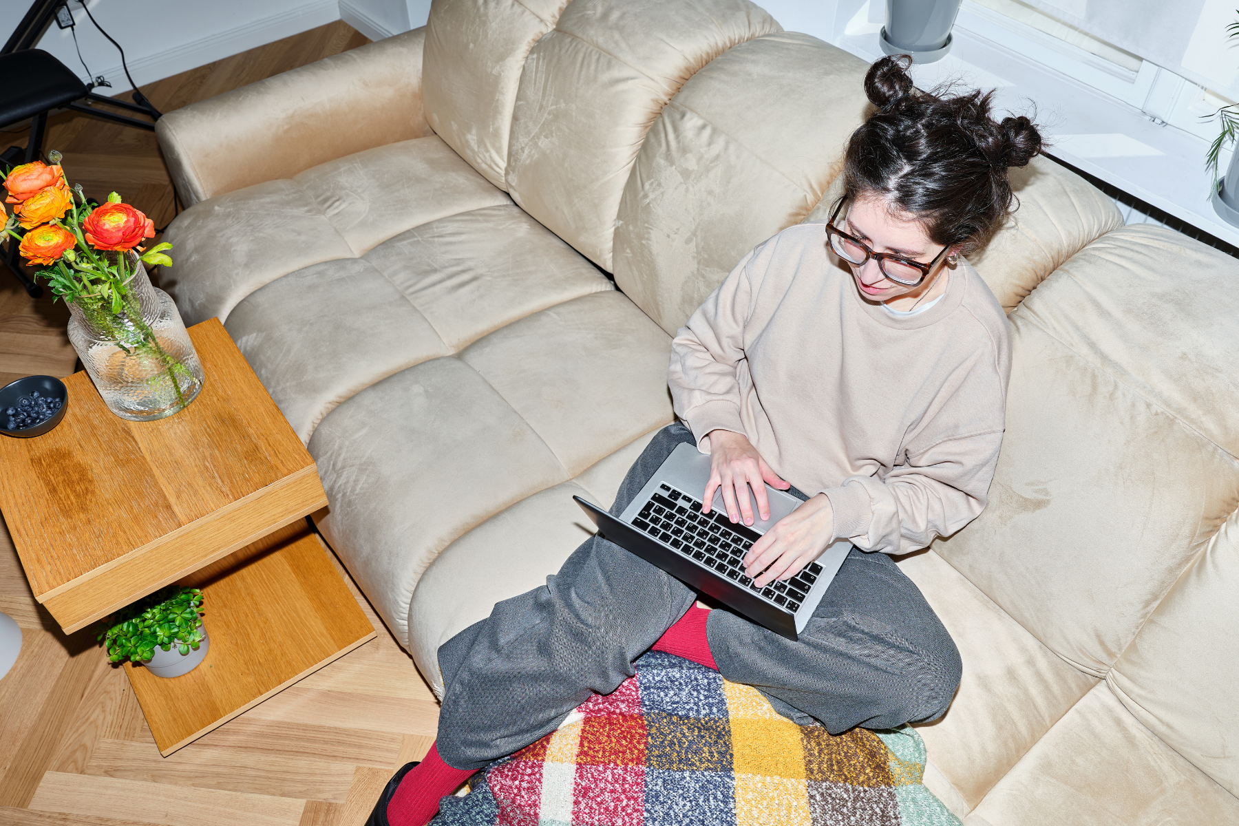 Jeune femme assise sur un divan avec un ordinateur portage sur ses genoux