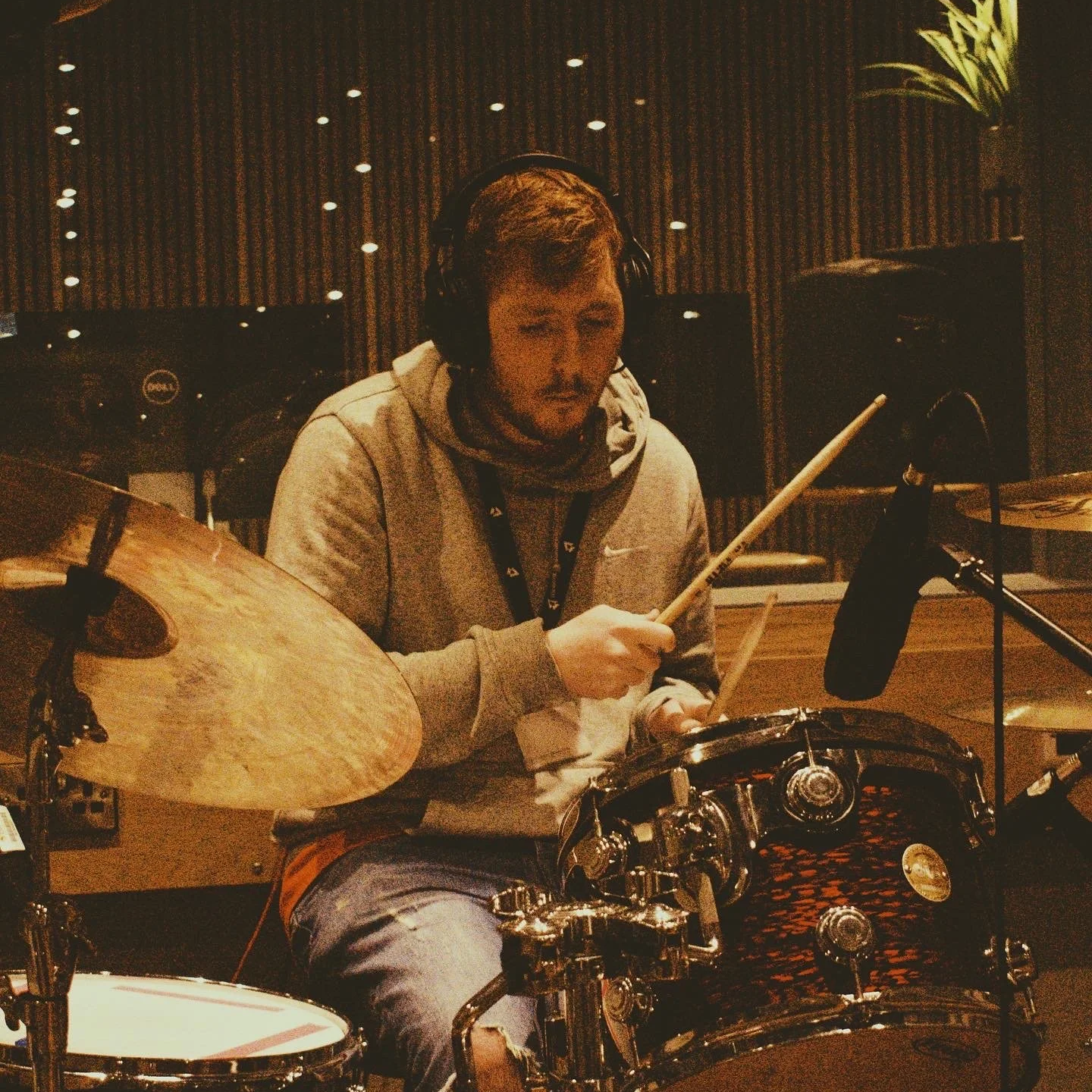 A man wearing headphones playing a drum set in a recording studio. Recording for Bad Luck Social Club/Picture Day at BIMM Brighton. Tracking drums.