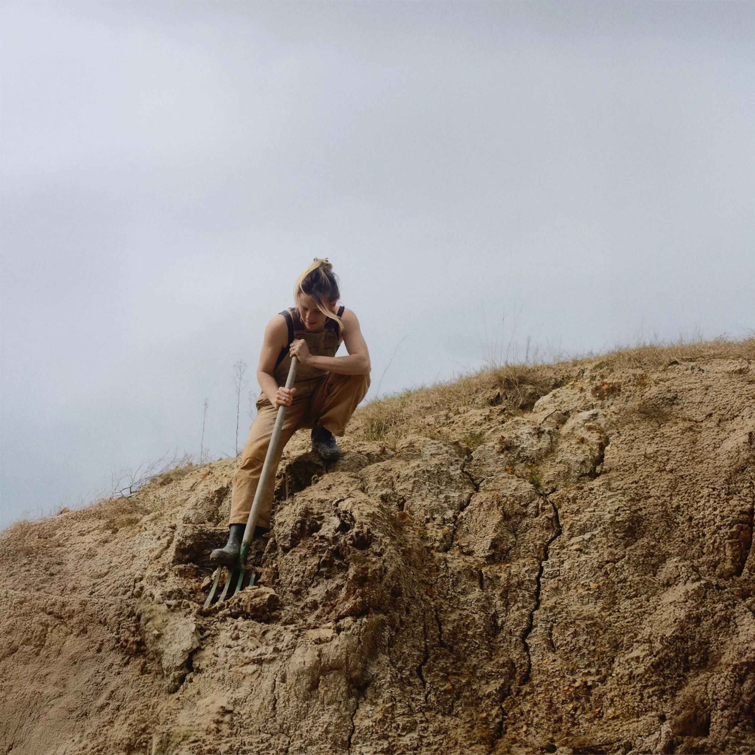 Une femme en vêtements de travail, équipée d'une pelle, excavant dans un terrain soil