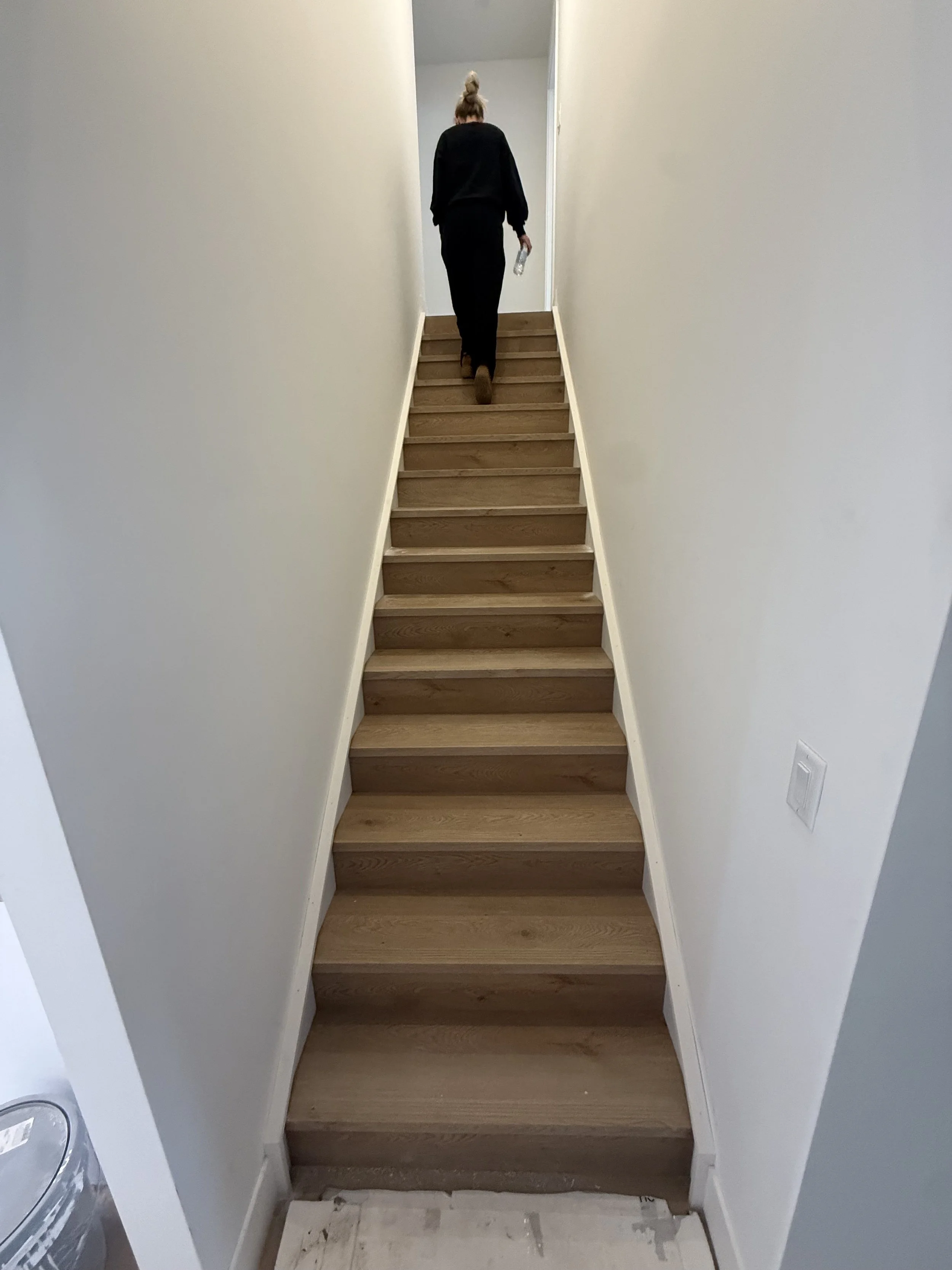 Interior view of a staircase in a home with white walls and wooden steps.