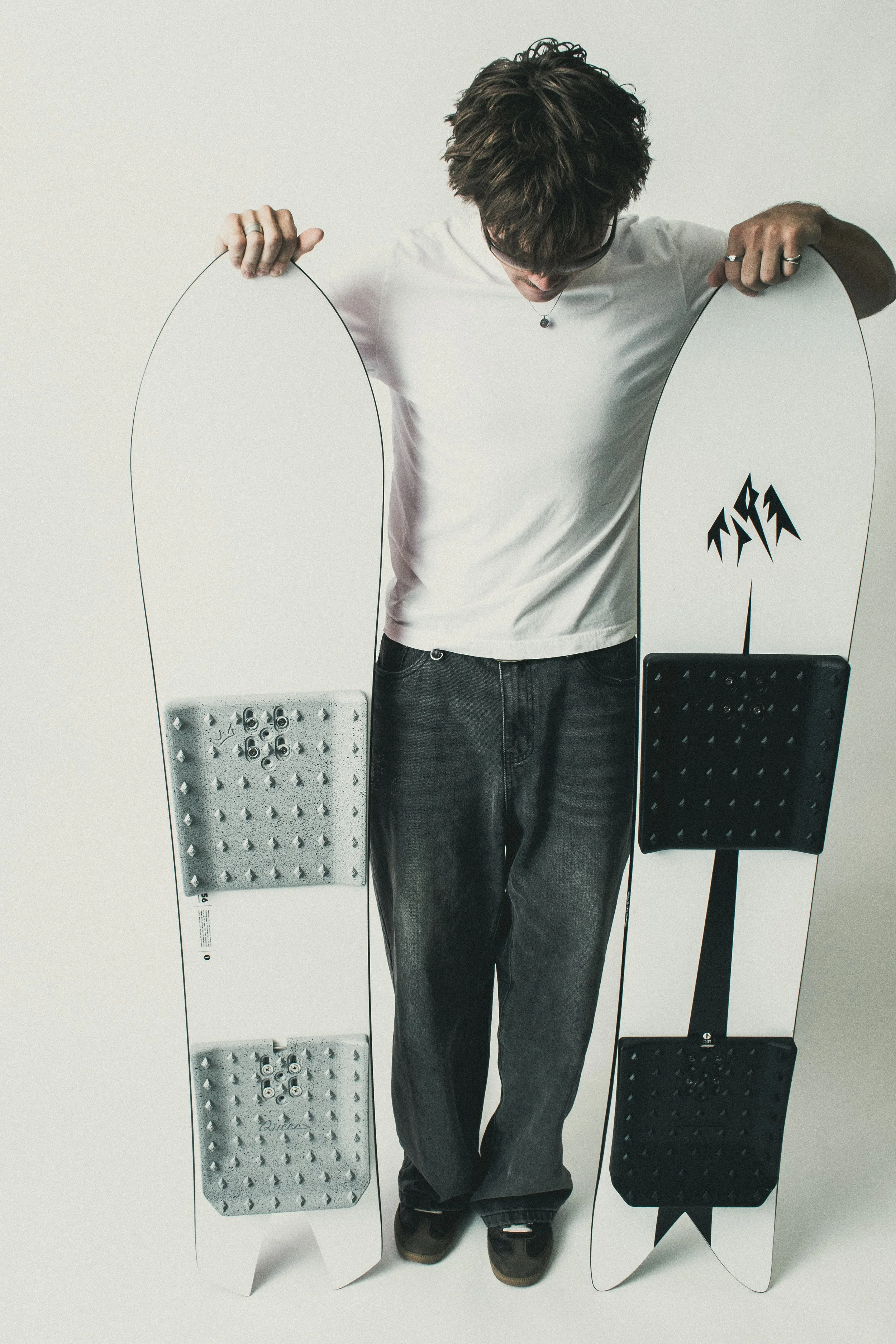 Rider standing between two snowboards fitted with Concrete and Black Solid Pads