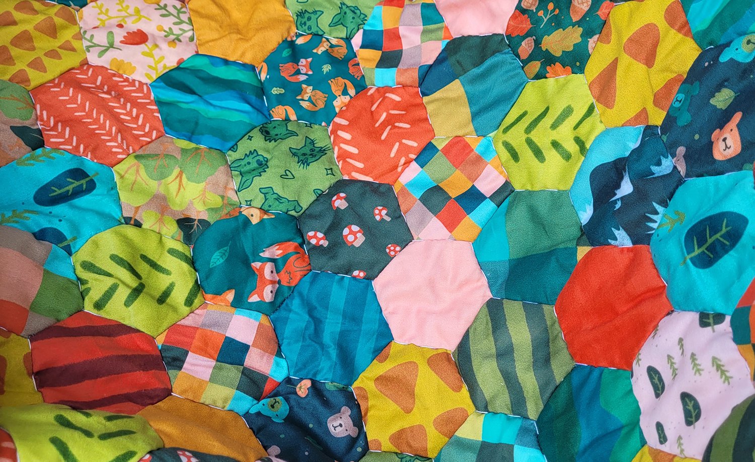 Close up of hand-quilted hexagon quilt in bright colored patterns