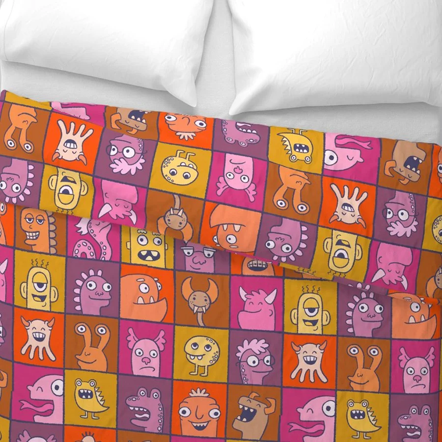 A brightly colored illustrated pattern of monster in individual boxes mocked up on a duvet cover