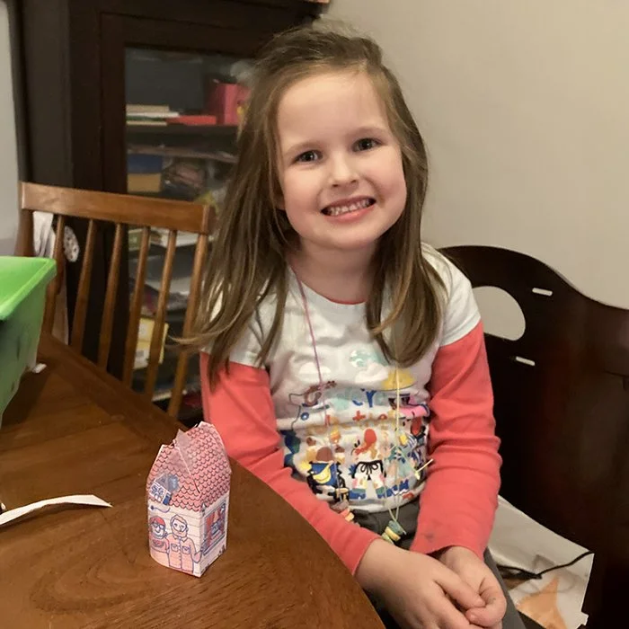 Small girl smiles next to the folded house
