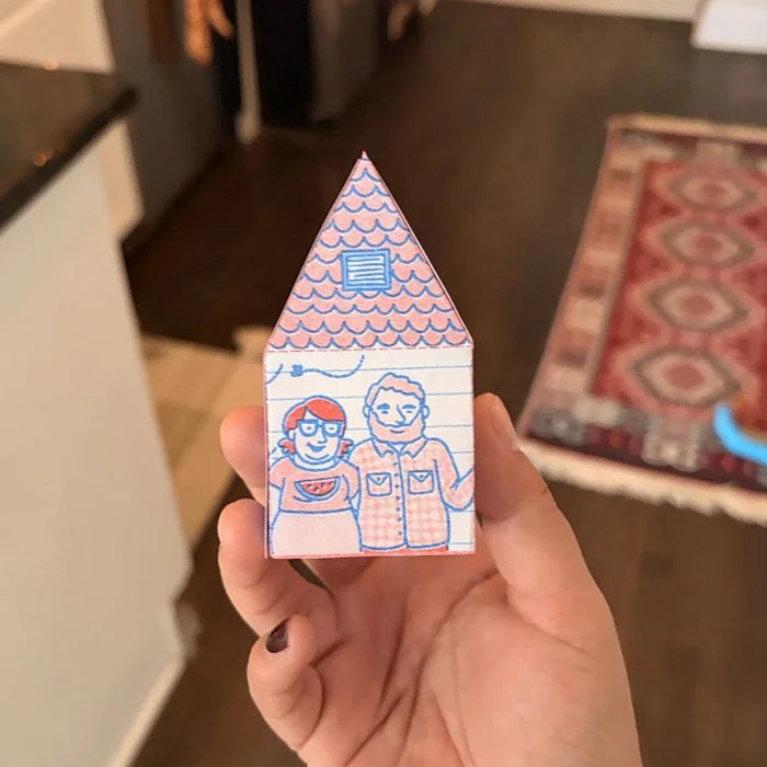 Hand holding the folded house in a kitchen