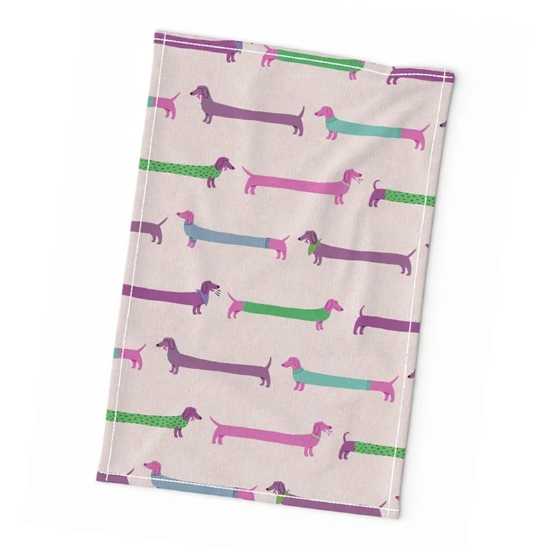 Mock-up of a tea towel with print featuring grape purple dachshunds wearing sweaters and other accessories
