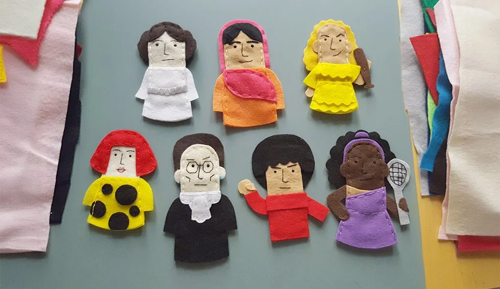 Felt finger puppets laying on a table. People represented include Princess Leia, Malala, Beyonce, Yayoi Kusama, Ruth Bader Ginsburg, Angela Davis, Serena Williams