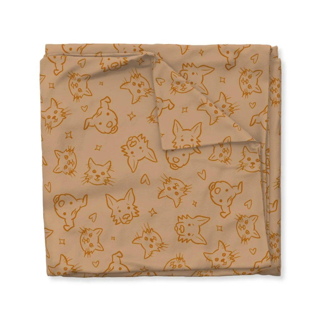 Mock-up of a folded piece of fabric featuring a pattern with light brown background and drawings of two dogs and two cats in dark orange