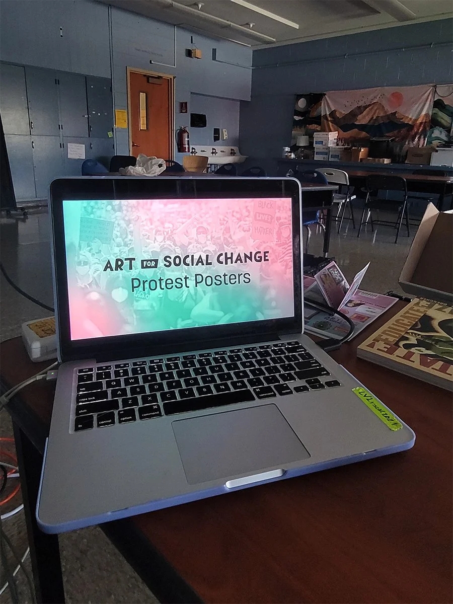 Laptop with slide that says "Protest Art" in a dark classroom